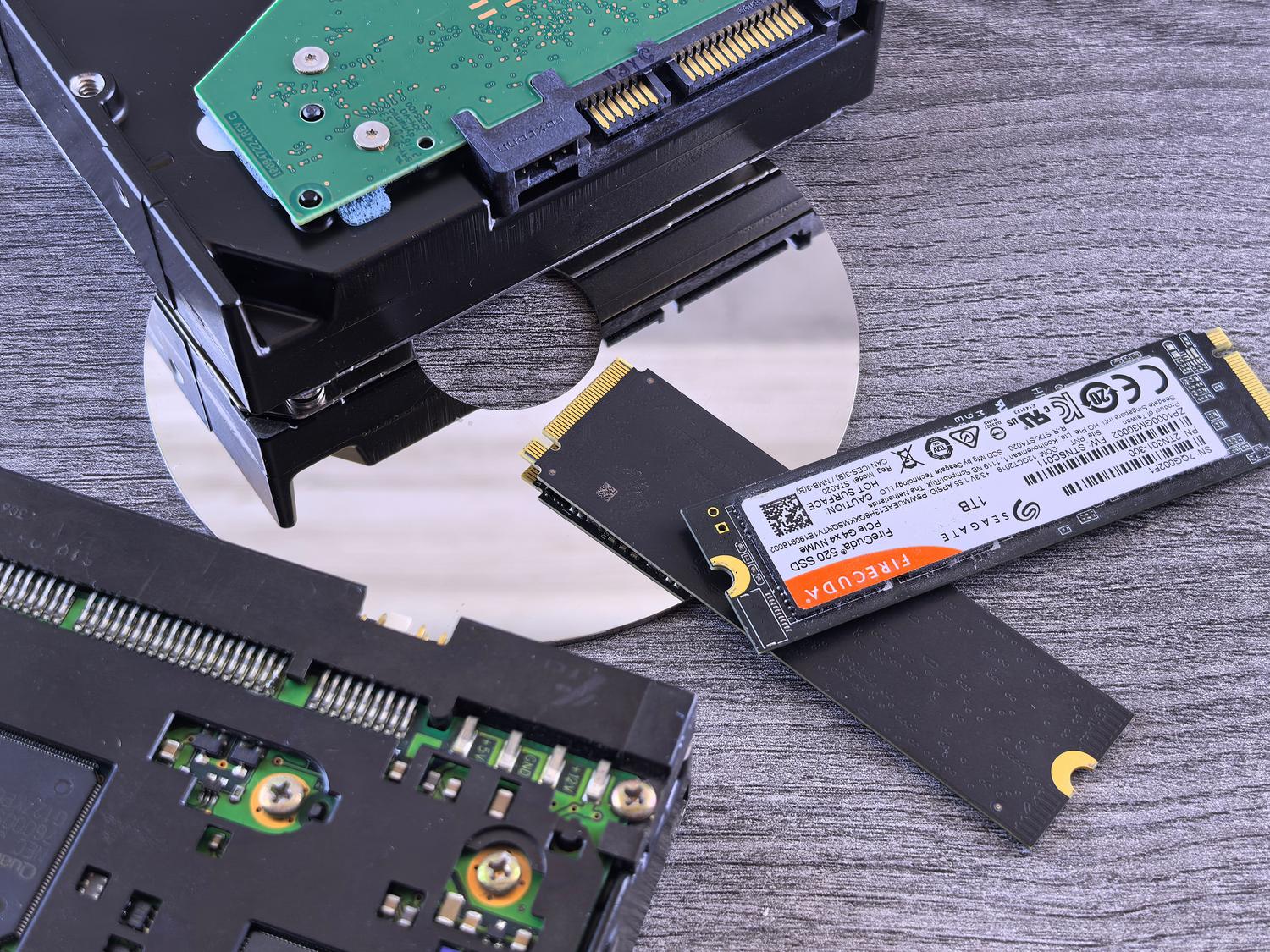 Comparativa visual de tecnologías de almacenamiento: un disco duro mecánico (HDD), un SSD SATA y unidades SSD NVMe M.2 sobre un fondo neutro.