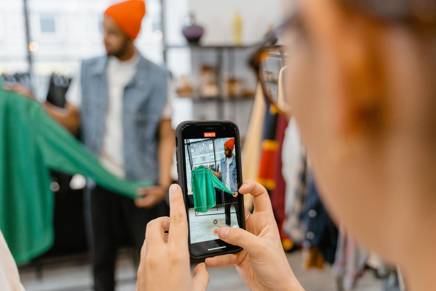 Persona utilizando la cámara de su smartphone para fotografiar una prenda de vestir en una tienda, ilustrando la búsqueda visual impulsada por IA.