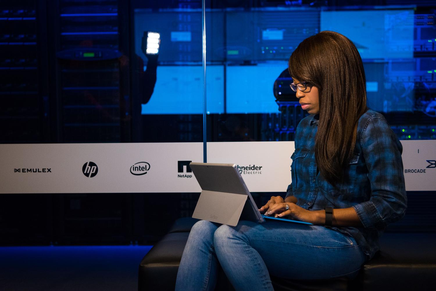 An IT professional using a portable device to manage server racks in a data center, illustrating the connection between a remote client and a server.