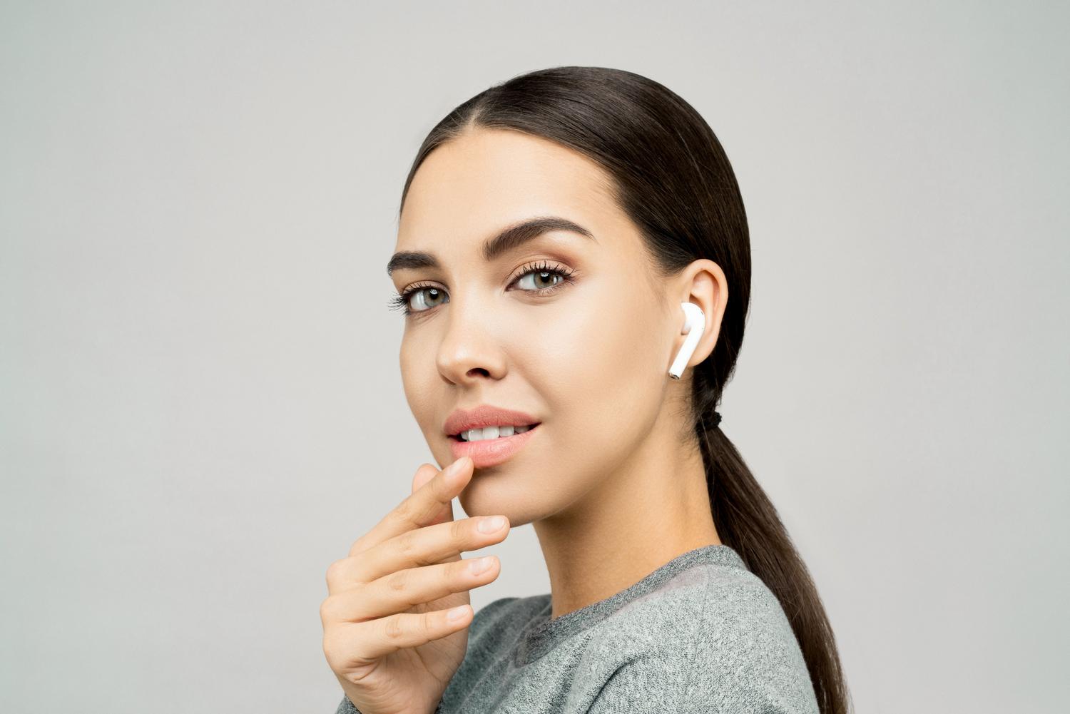 Retrato de una mujer sonriendo con auriculares inalámbricos, representando la facilidad de uso de la tecnología de traducción.