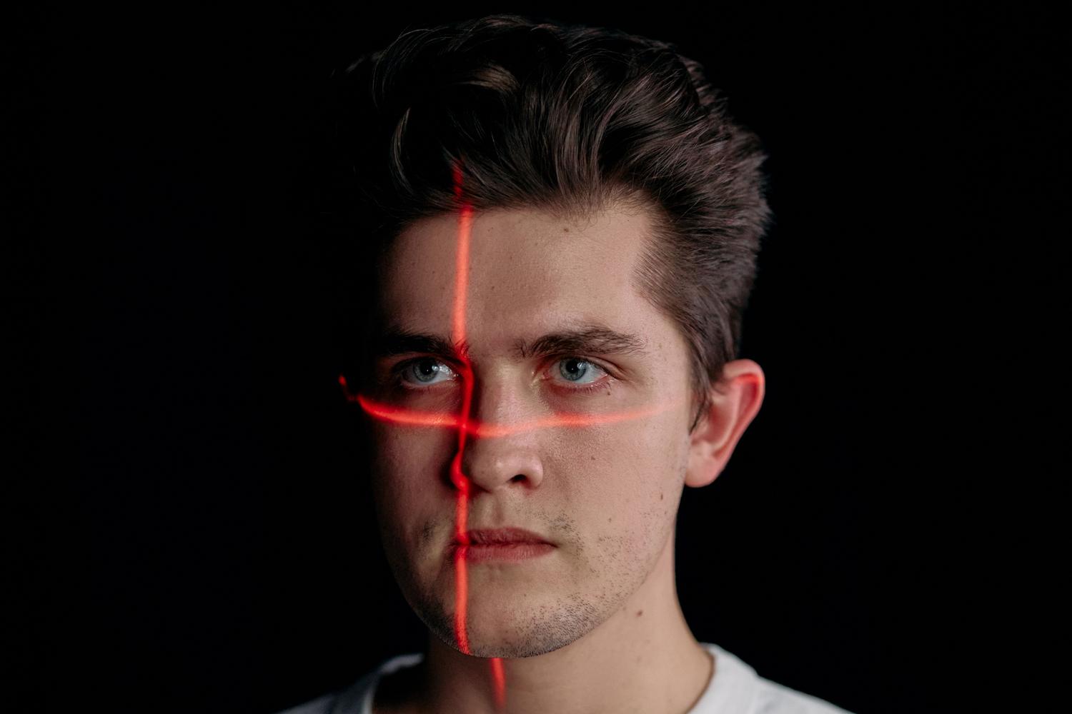 Retrato de reconocimiento facial con escaneo láser rojo, ilustrando la biometría y la identidad digital.