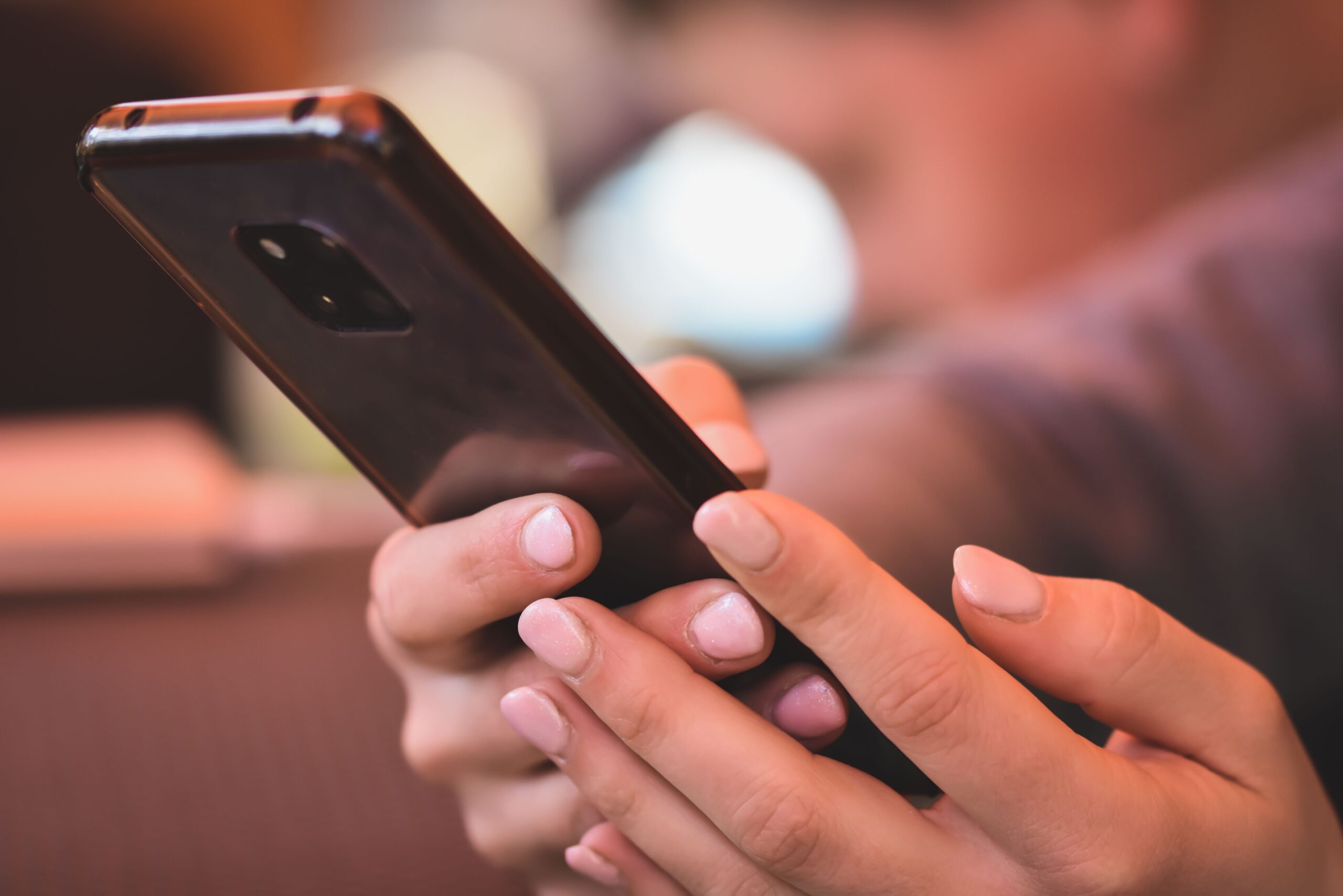 Manos sosteniendo un smartphone moderno en un entorno profesional y neutro.