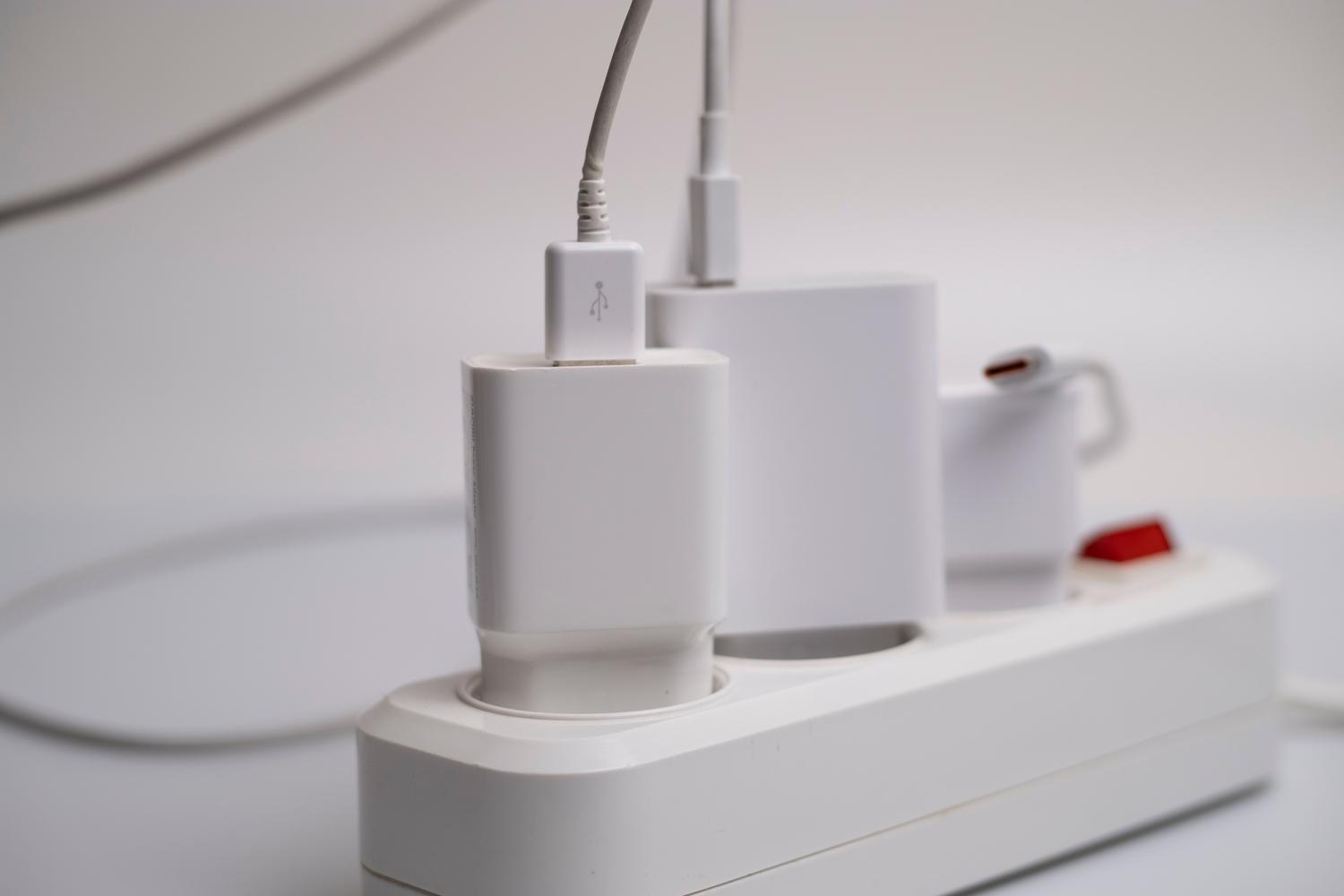 Cargadores de dispositivos electrónicos conectados a una regleta, ejemplificando el consumo fantasma o modo standby.