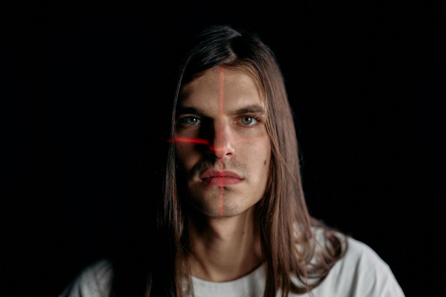 Hombre joven con una rejilla de láseres rojos sobre su cara, simbolizando el análisis técnico para diferenciar deepfakes de fotos reales.