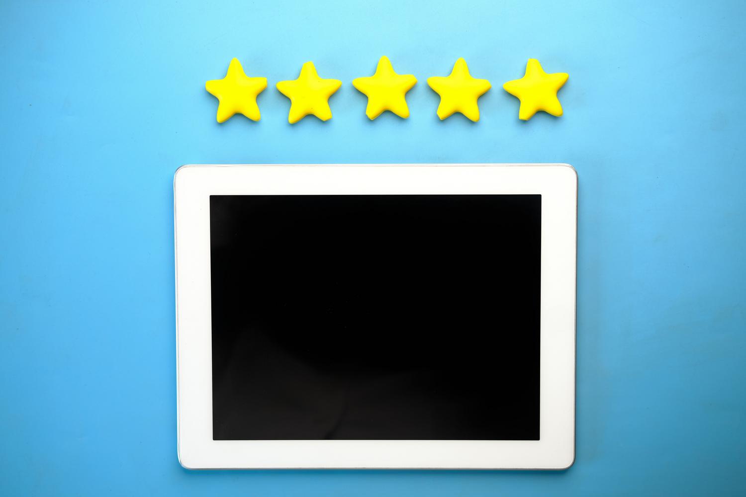 Tablet con cinco estrellas amarillas sobre un fondo azul, simbolizando la valoración y la reputación digital positiva.