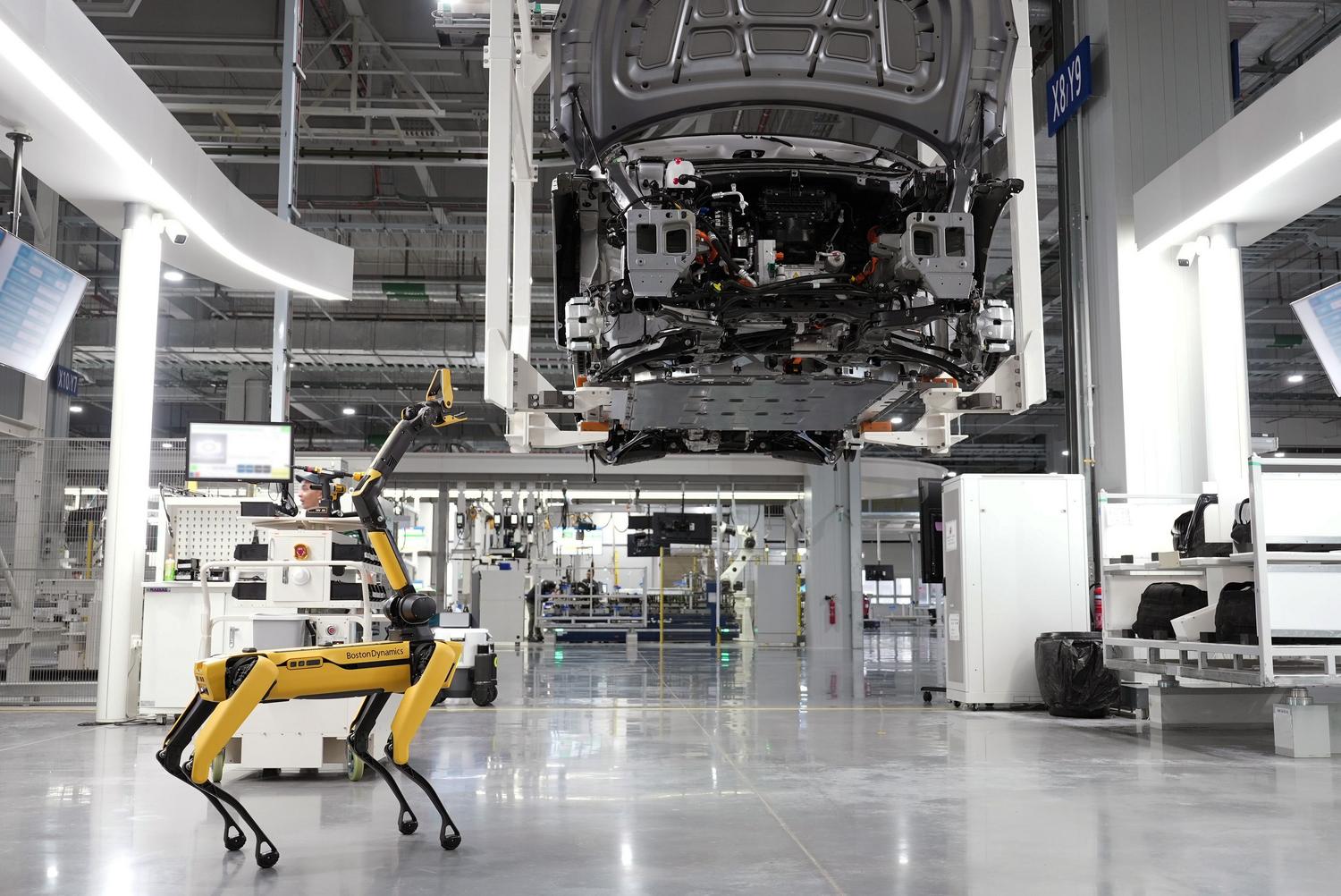 Robot cuadrúpedo autónomo en una fábrica de automóviles inteligente, representando un ecosistema de IoT industrial (IIoT) de alta tecnología.