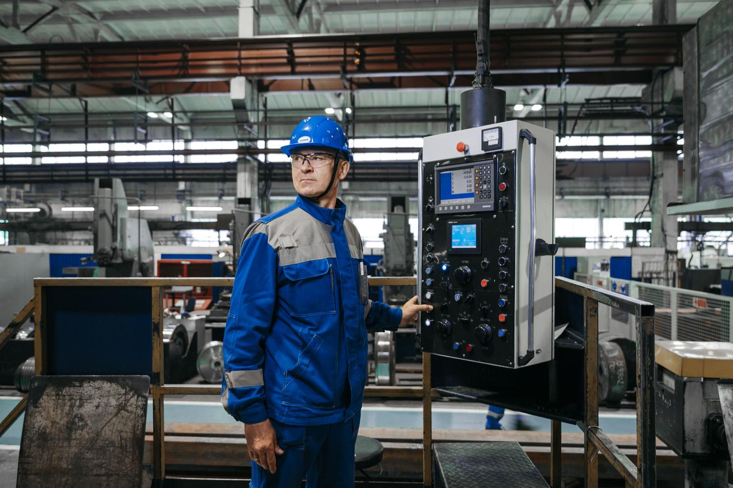 Operario industrial interactuando con un panel de control digital complejo, destacando el factor humano y la necesidad de capacitación técnica.