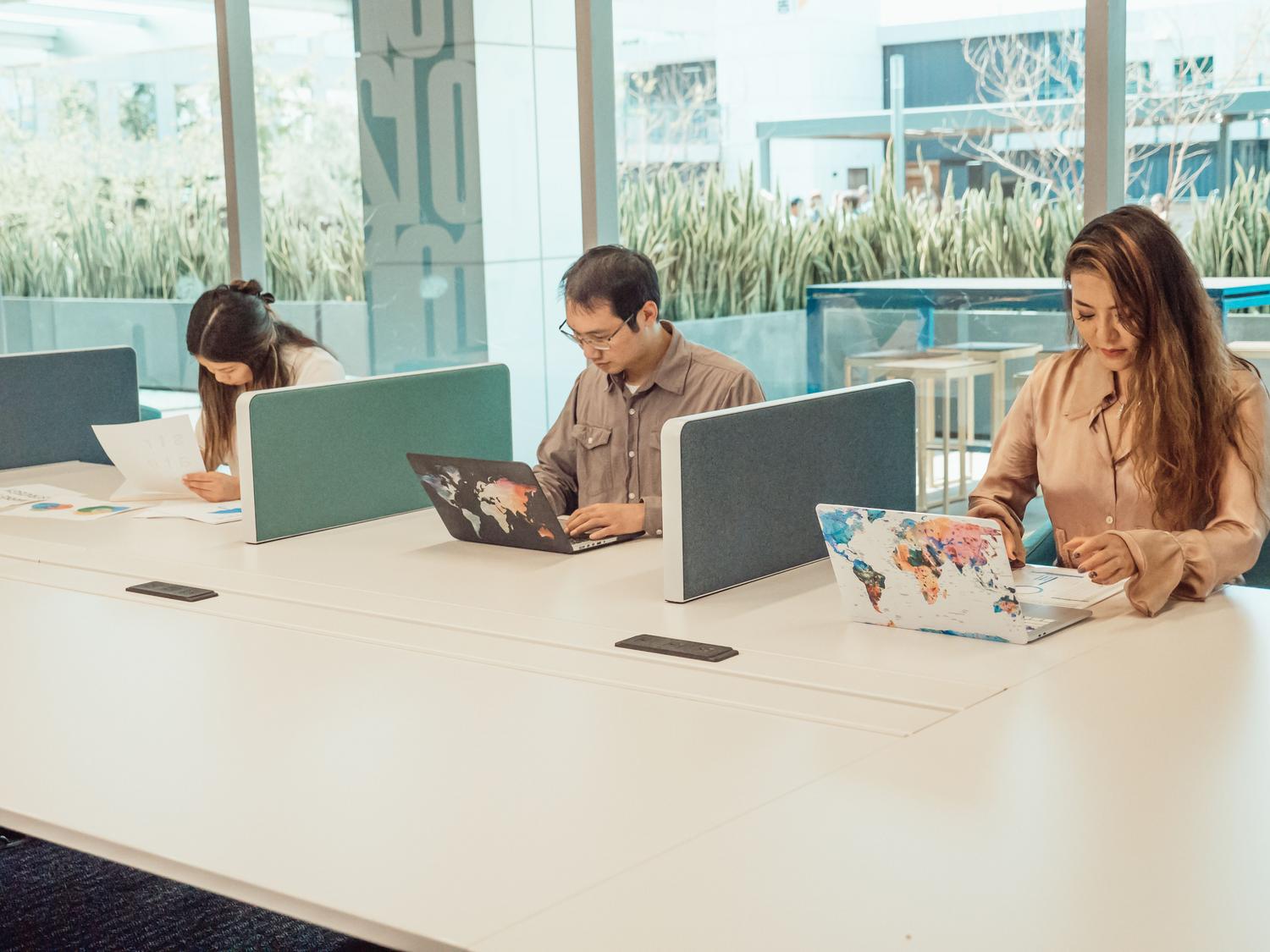 Espacio de trabajo digital colaborativo con empleados utilizando diversas herramientas de Google Workspace en una oficina abierta.