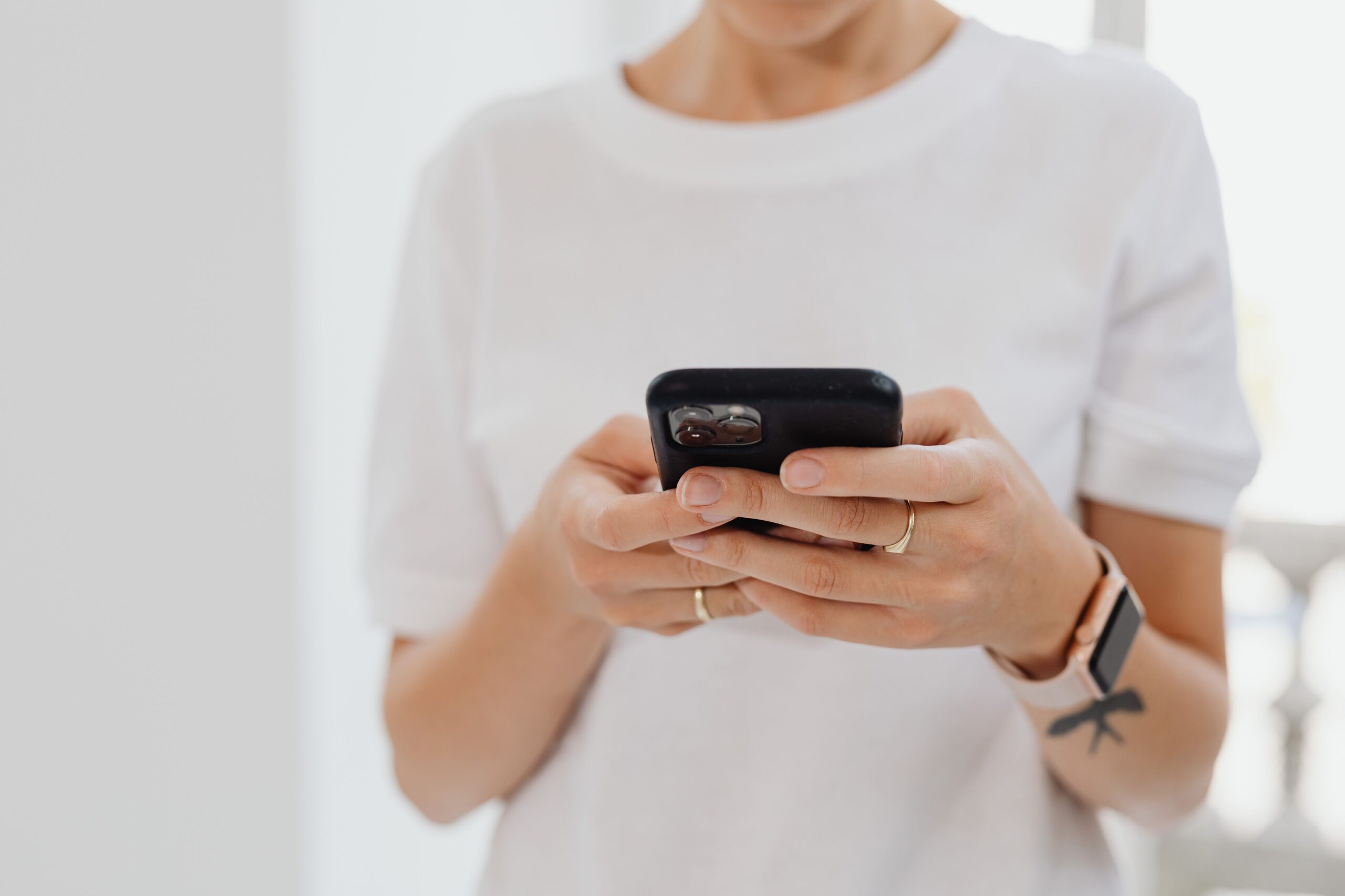Mujer utilizando un smartphone en interiores, ilustrando el uso diario de las funciones de iOS.