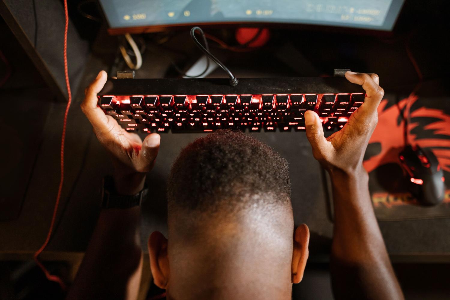 Gamer expresando frustración al levantar el teclado, representando el impacto negativo de los tirones y la pérdida de FPS.
