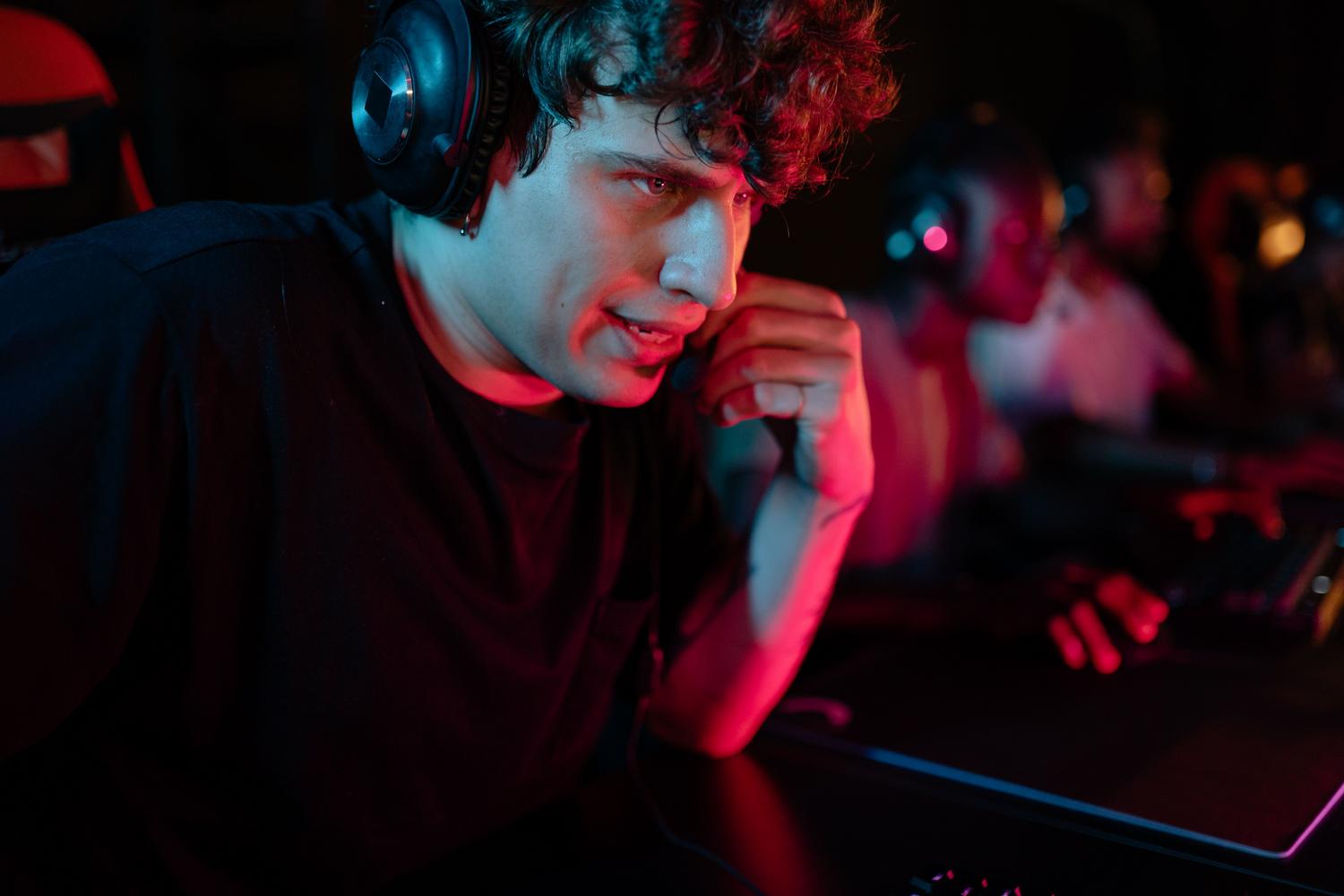 Primer plano de un gamer concentrado con auriculares en un ambiente oscuro, ilustrando la experiencia de inmersión del usuario.
