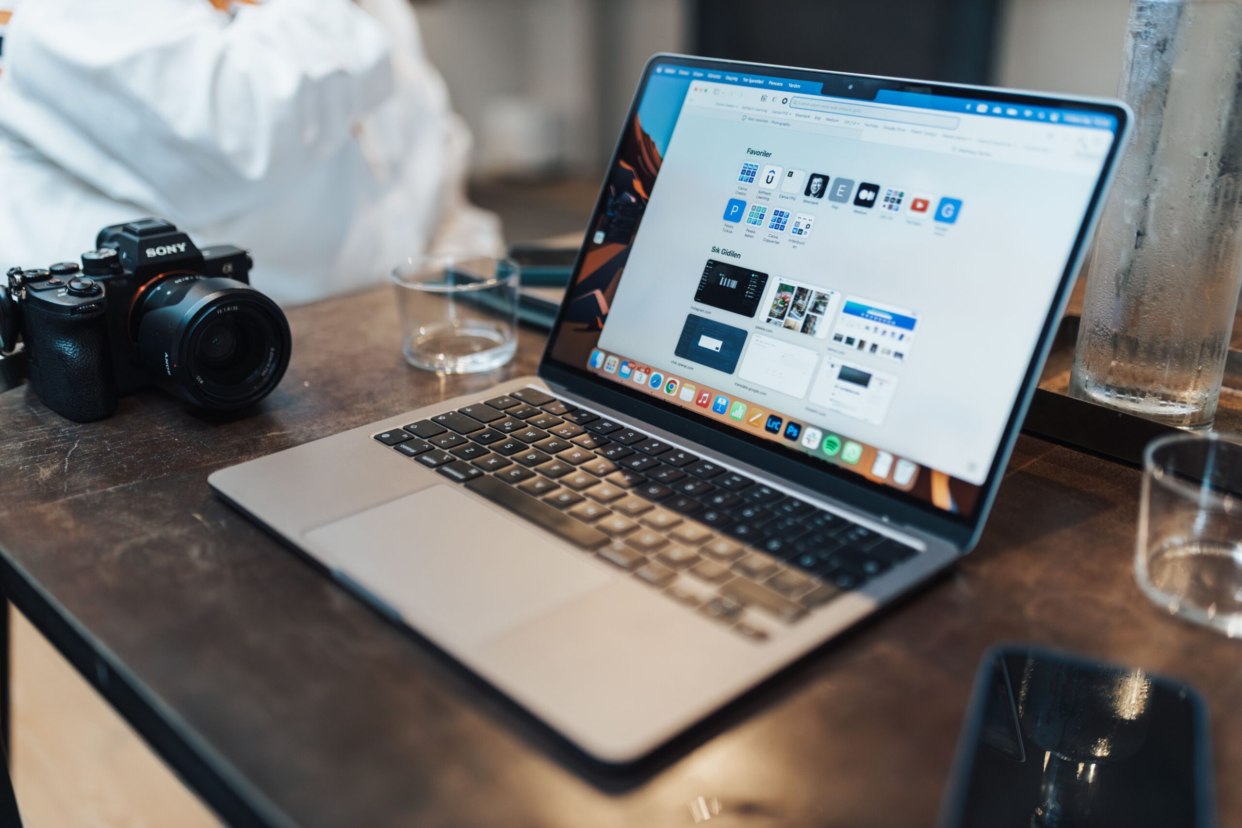 Espacio de trabajo tecnológico y minimalista con un ordenador portátil y una cámara fotográfica sobre una mesa gris
