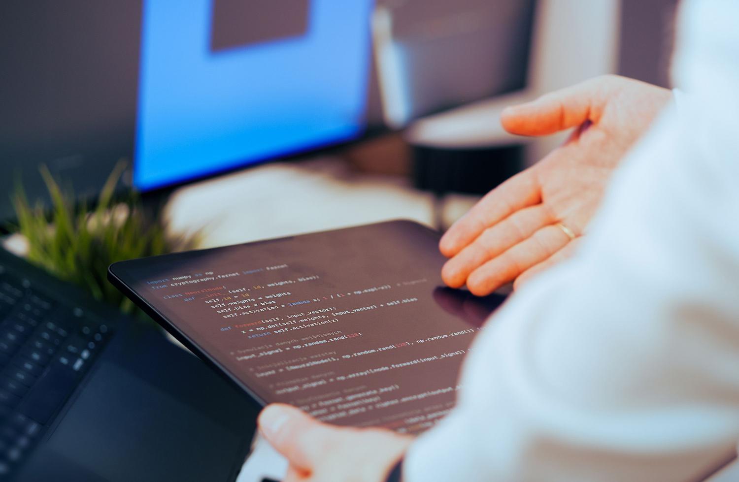 Desarrollador revisando código en una tablet, simbolizando el proceso de verificación y la implementación del patrón Escritor/Revisor.