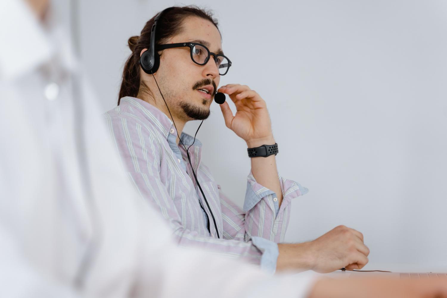 Agente de soporte técnico con auriculares en una oficina moderna, ilustrando la comunicación con el equipo de soporte de Meta.