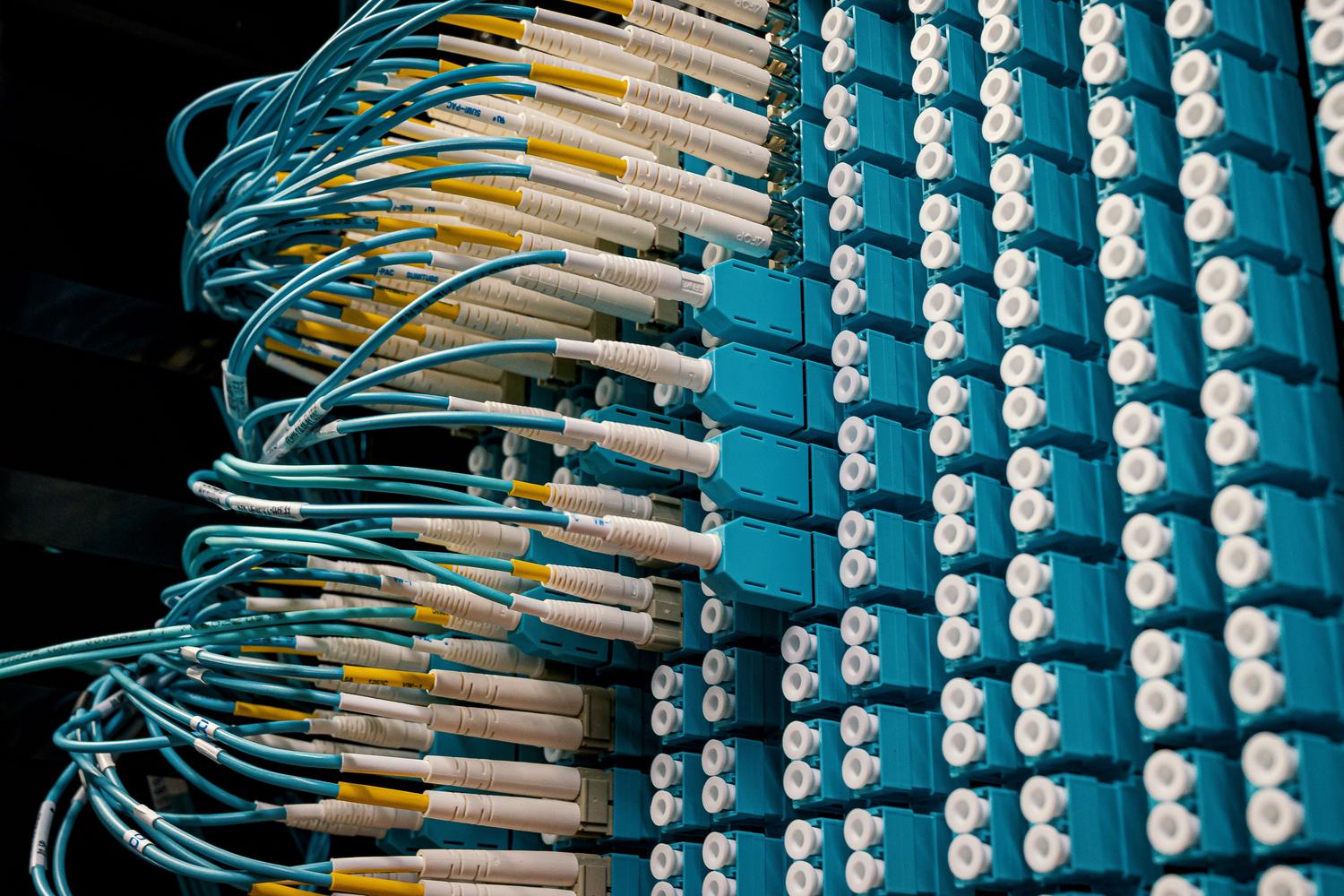 Cables de fibra óptica conectados a un panel de parcheo, ilustrando la interconexión de alta velocidad.