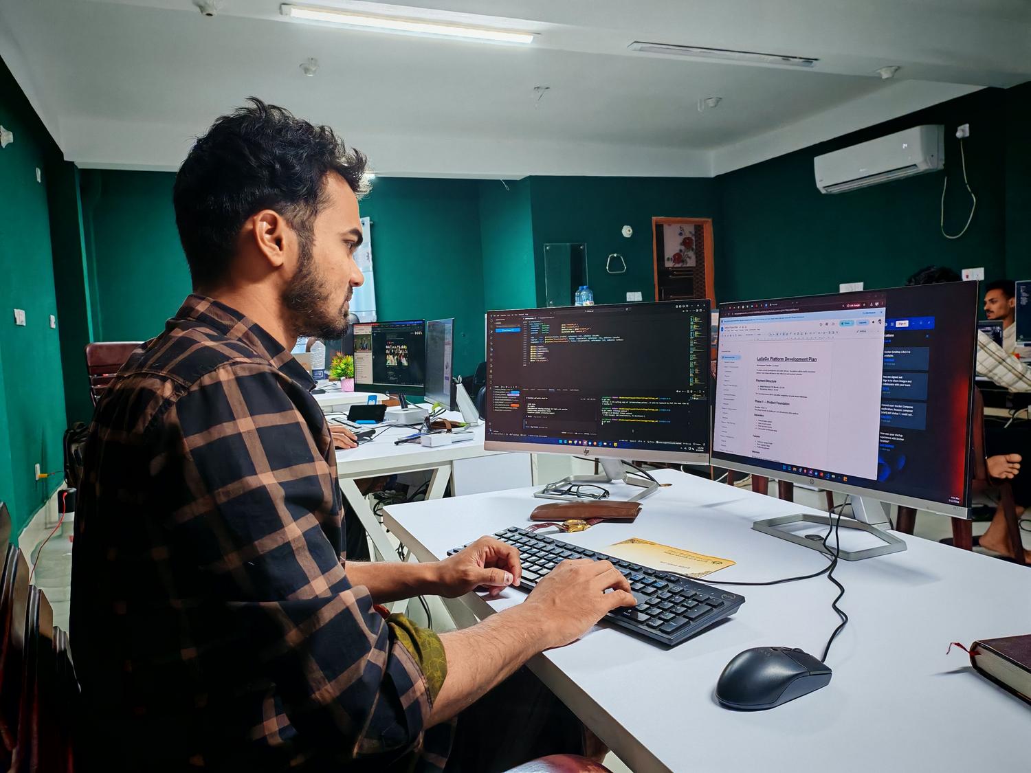 Desarrollador profesional con configuración de doble monitor gestionando el código y el plan de desarrollo de un proyecto.