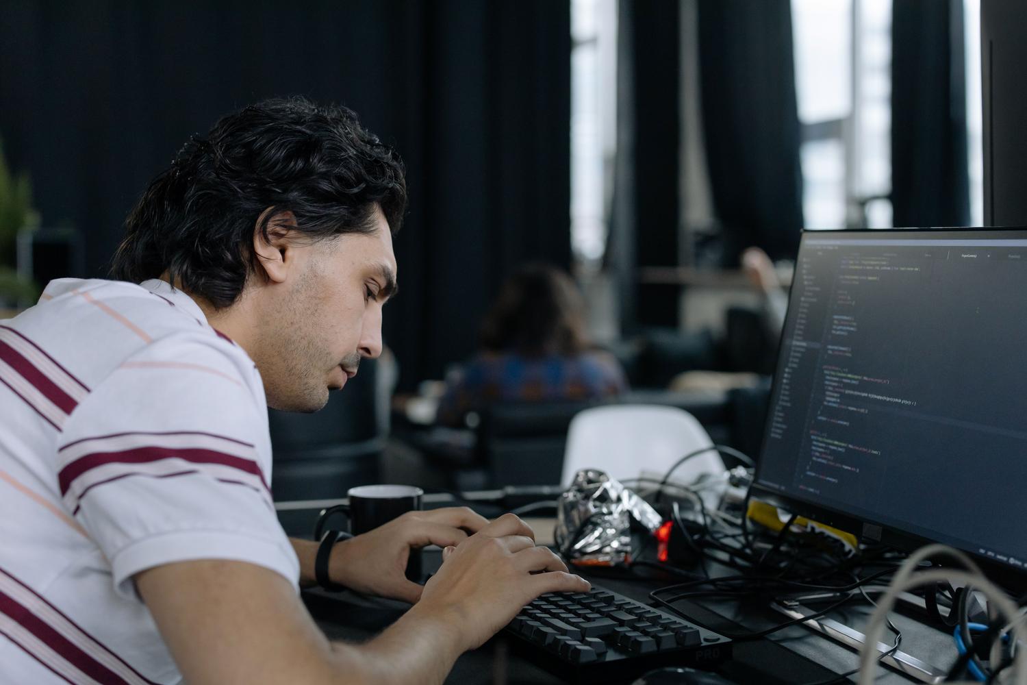 Programador concentrado escribiendo líneas de código en un entorno de trabajo moderno.