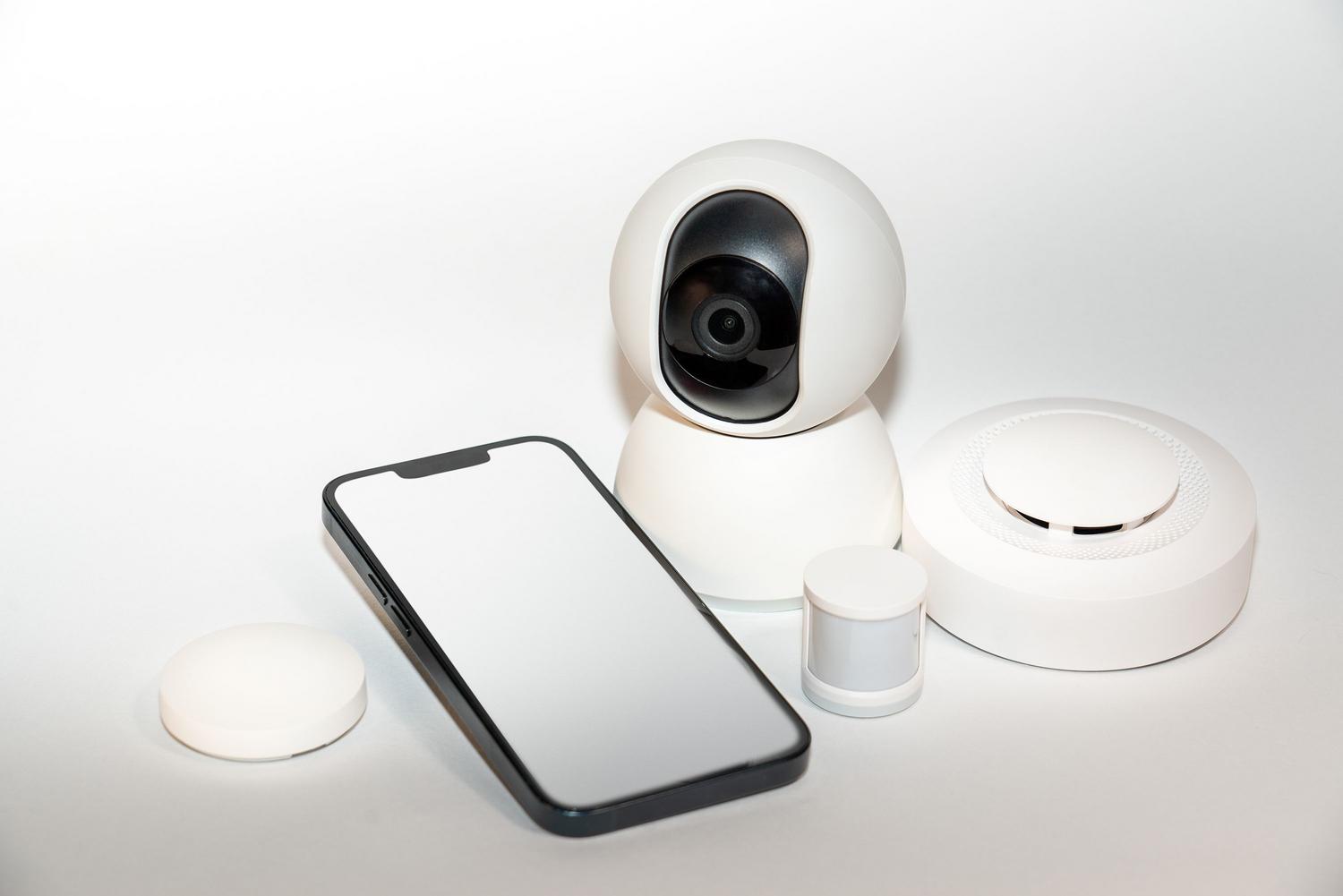 Conjunto de dispositivos de seguridad inteligente para el hogar con un teléfono móvil mostrando la interfaz de control.