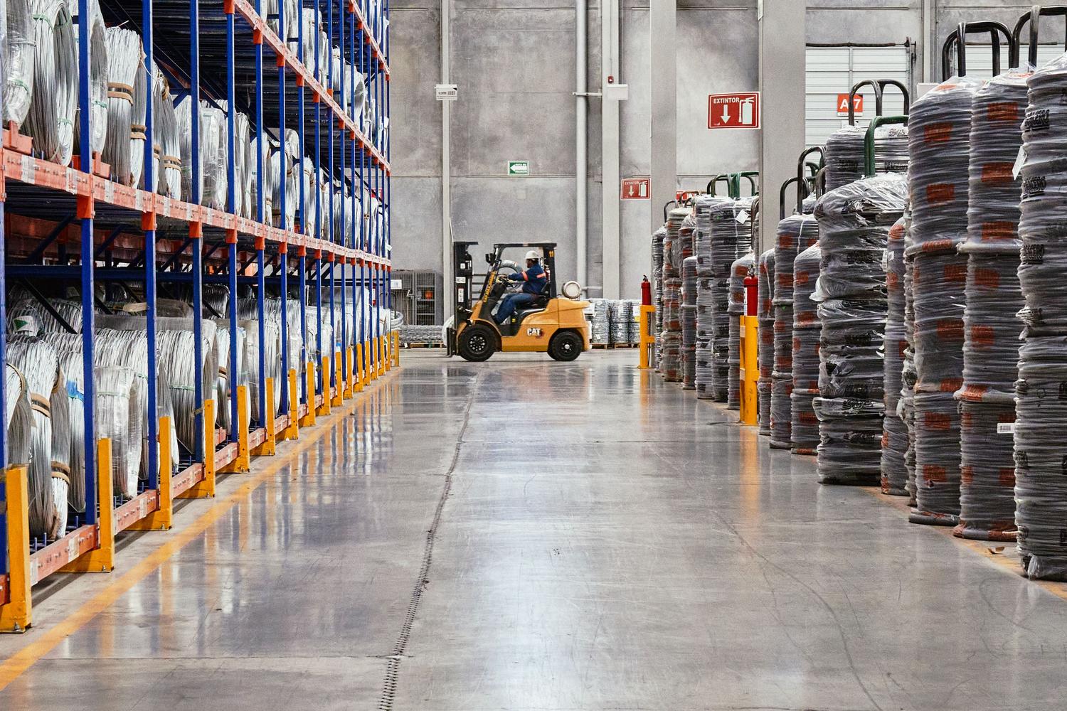 Operación de carretilla elevadora en un almacén industrial, entorno donde se aplican sistemas de seguridad inteligente para prevenir colisiones.