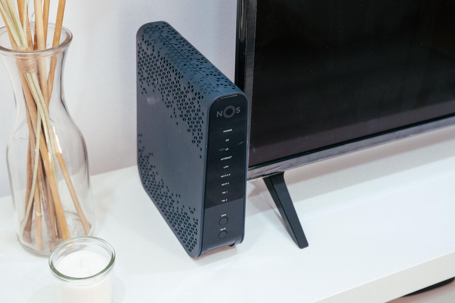 Router WiFi colocado sobre un mueble a altura media en un salón, optimizando la propagación de la señal.