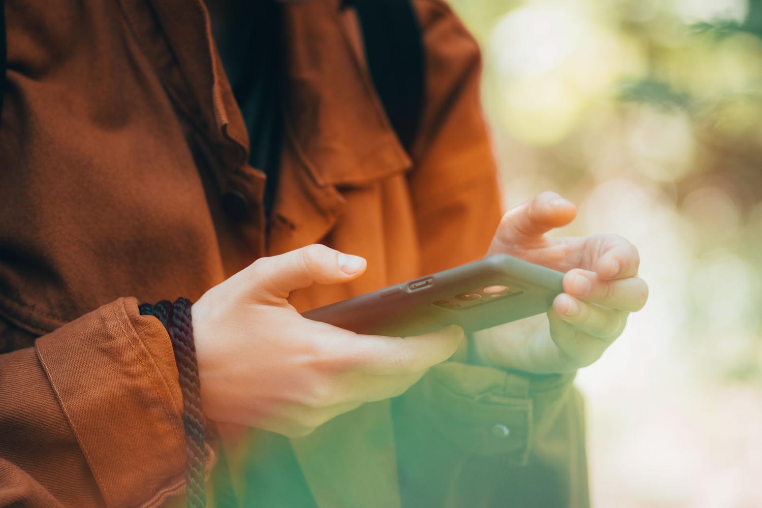 Primer plano de manos operando un smartphone en el exterior, simulando el acceso a los ajustes de configuración de la cuenta.