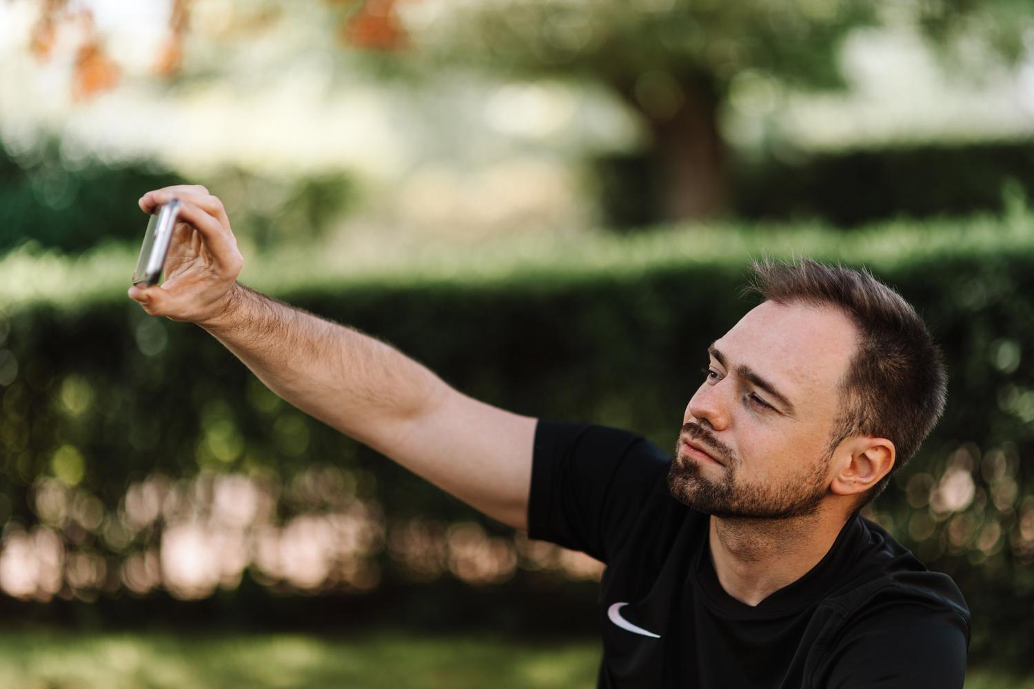 Hombre joven tomándose un selfie con su móvil, ilustrando el proceso de grabación del video selfie para la verificación de identidad.