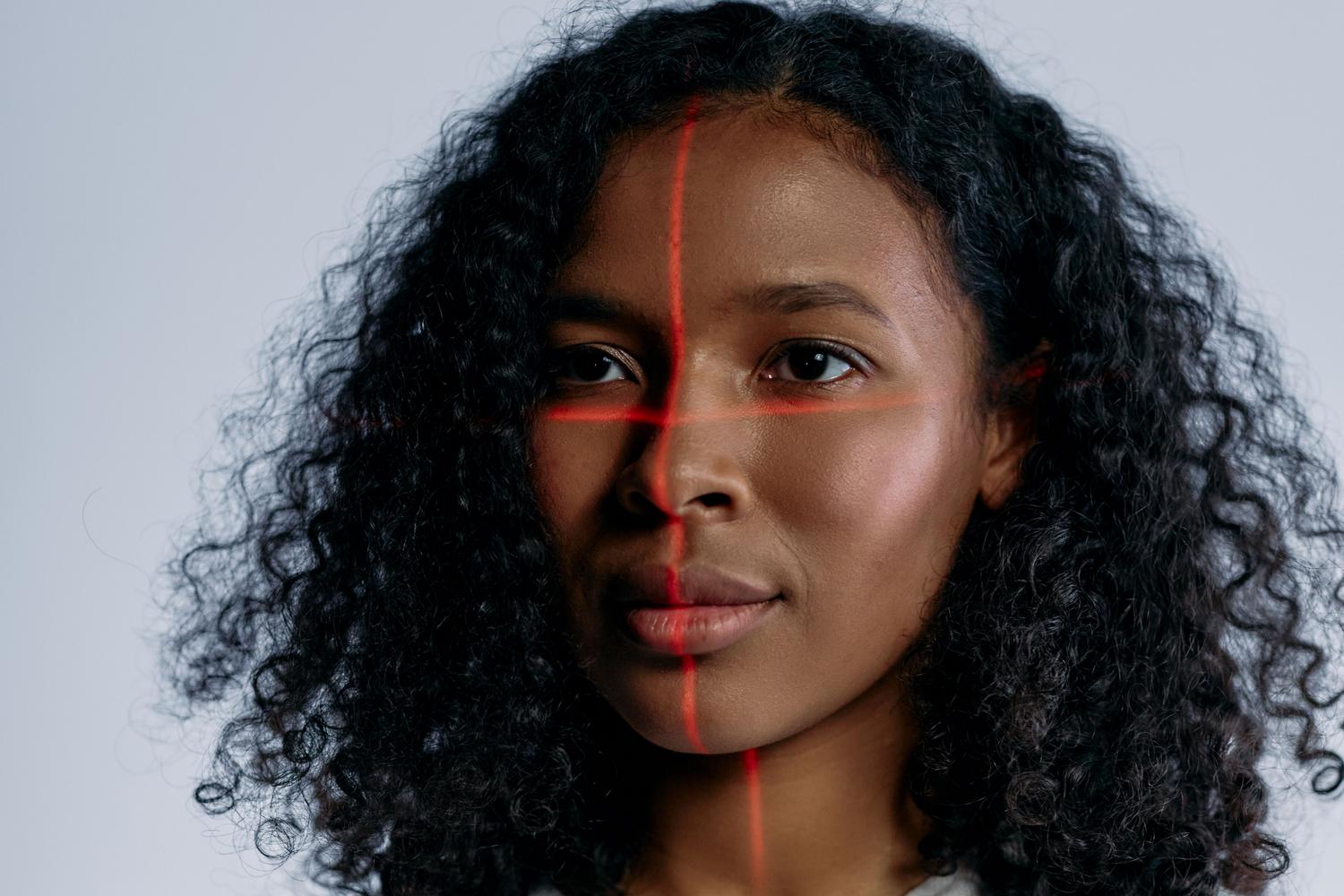 Representación conceptual de tecnología de reconocimiento facial con escaneo láser sobre el rostro de una mujer.