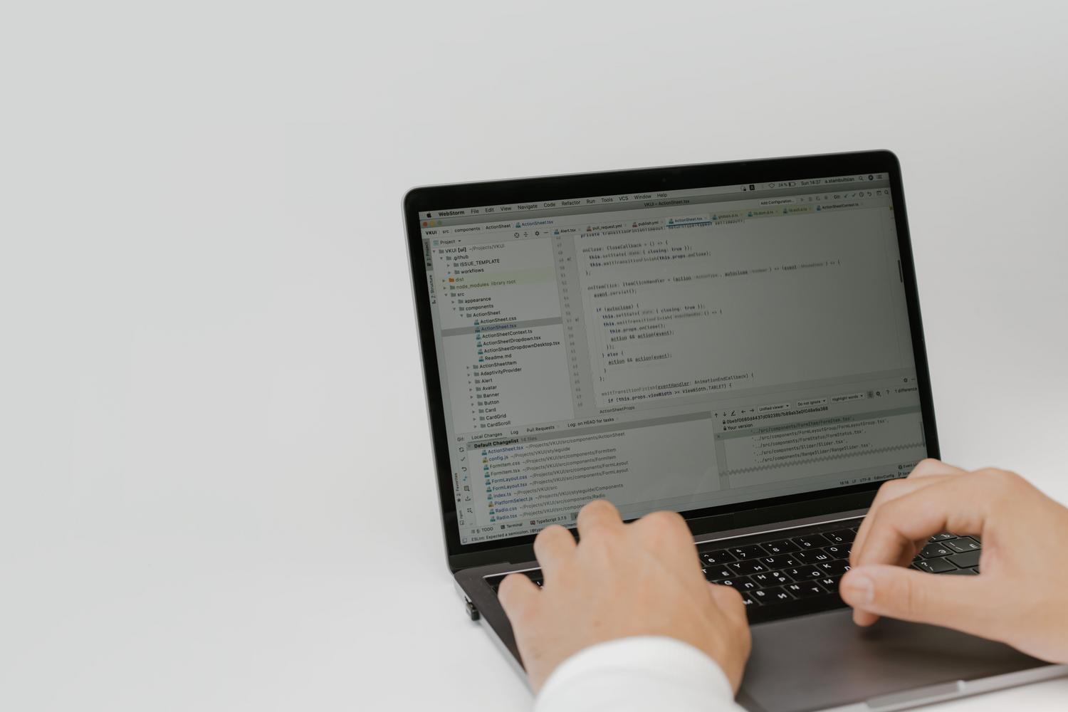 Manos escribiendo código en un teclado de portátil en un entorno profesional de software.