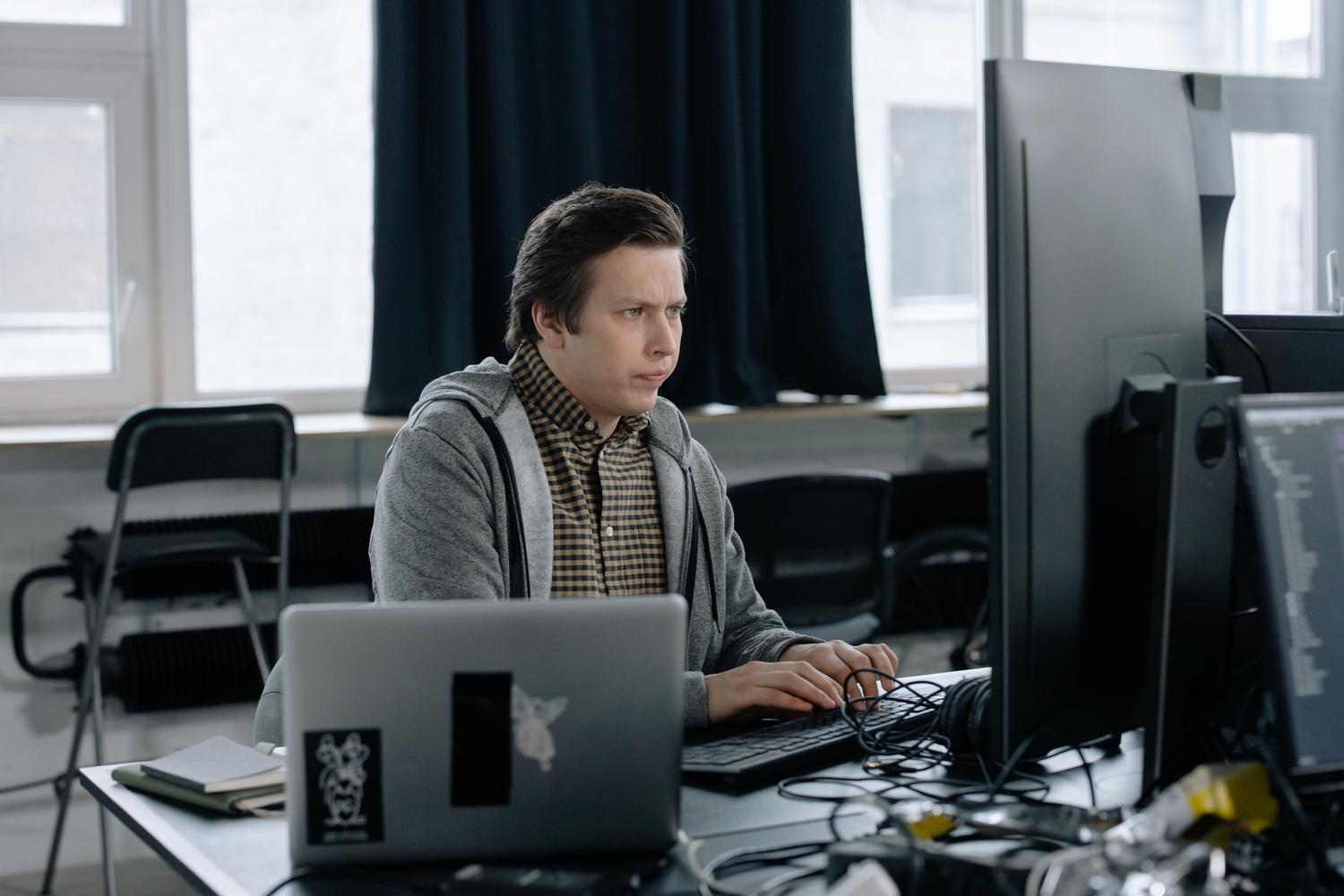 Programador profesional trabajando en un entorno de desarrollo con monitores duales, representando las distribuciones de Linux para perfiles técnicos.
