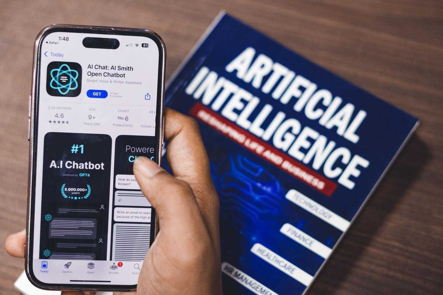 Smartphone mostrando una aplicación de chatbot de IA junto a un libro de inteligencia artificial, ejemplificando la IA en dispositivos móviles (edge).