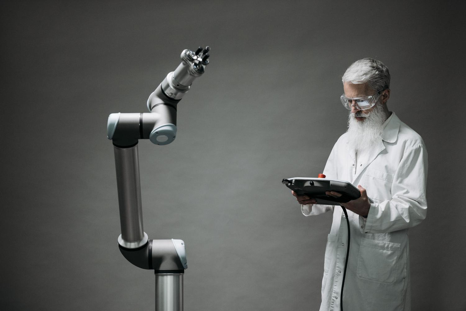 Científico operando un brazo robótico industrial, ilustrando la IA aplicada a la robótica y el edge computing en entornos de fabricación.