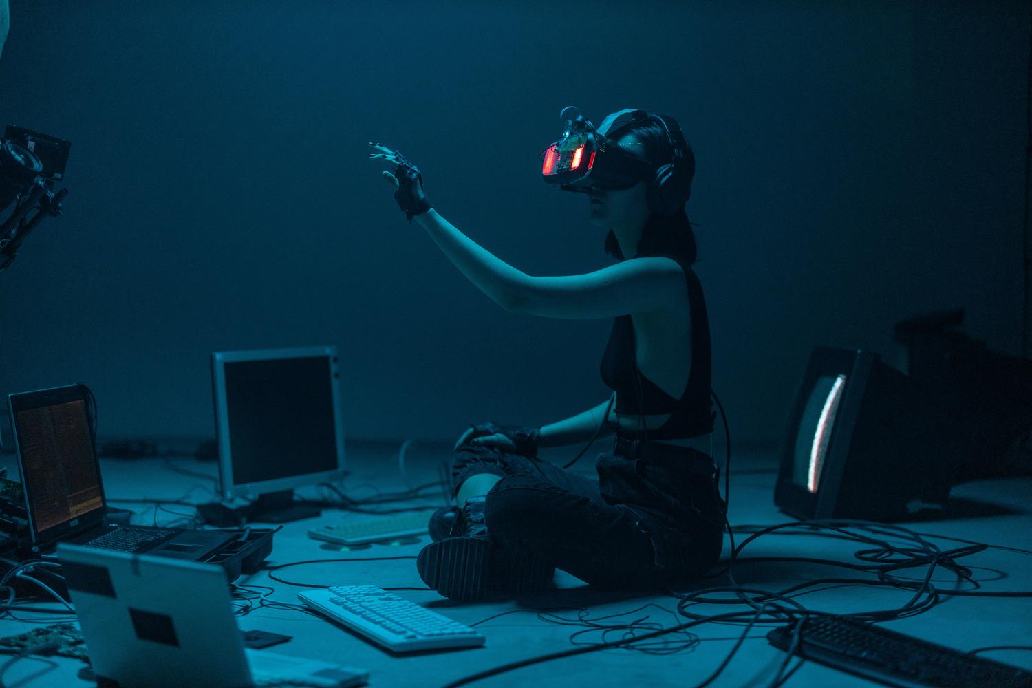 Persona utilizando un casco de realidad virtual y guantes hápticos con electrónica expuesta, simbolizando la computación en el límite y los wearables inteligentes.