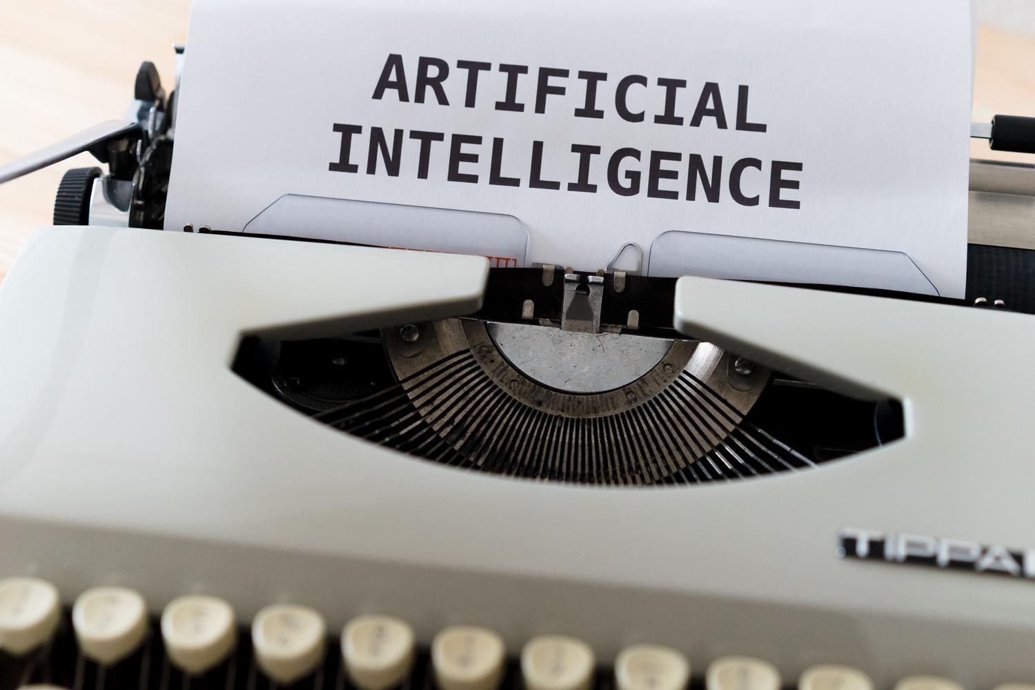 Máquina de escribir antigua con el texto 'ARTIFICIAL INTELLIGENCE', representando la evolución de la escritura hacia la IA.