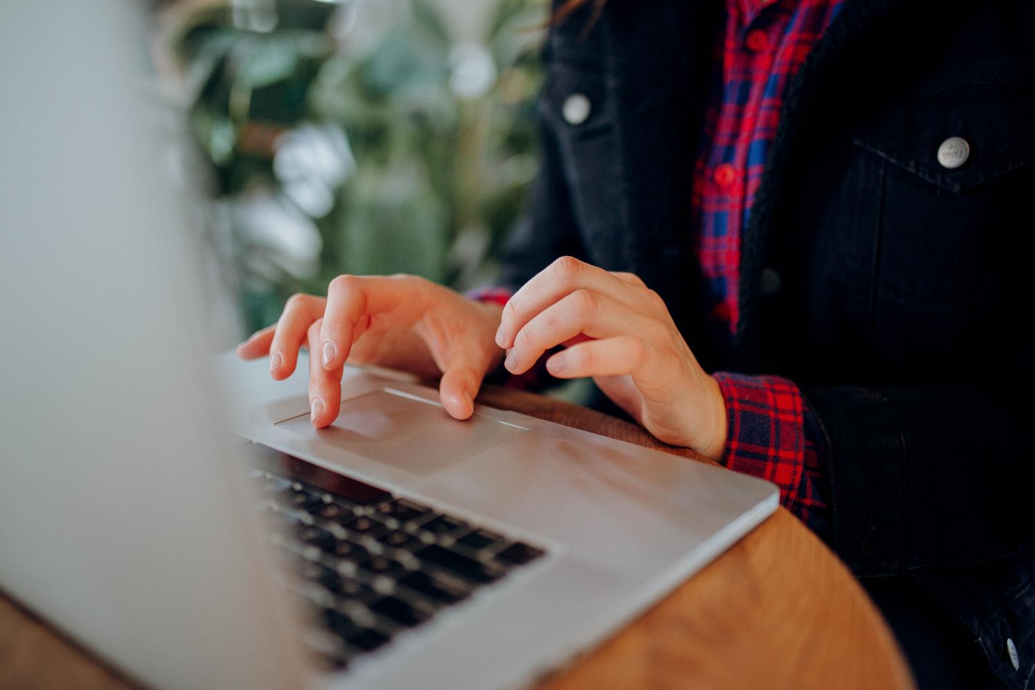 Primer plano de las manos de una persona escribiendo en el teclado de un ordenador portátil, representando la protección de carpetas en Windows y Mac.