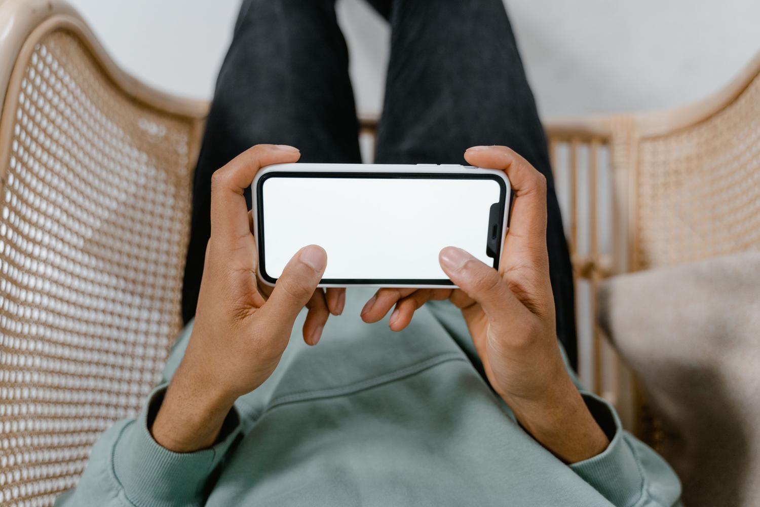 Una persona relajada sosteniendo un teléfono móvil con la pantalla en blanco, simbolizando la tranquilidad de tener los archivos respaldados automáticamente.