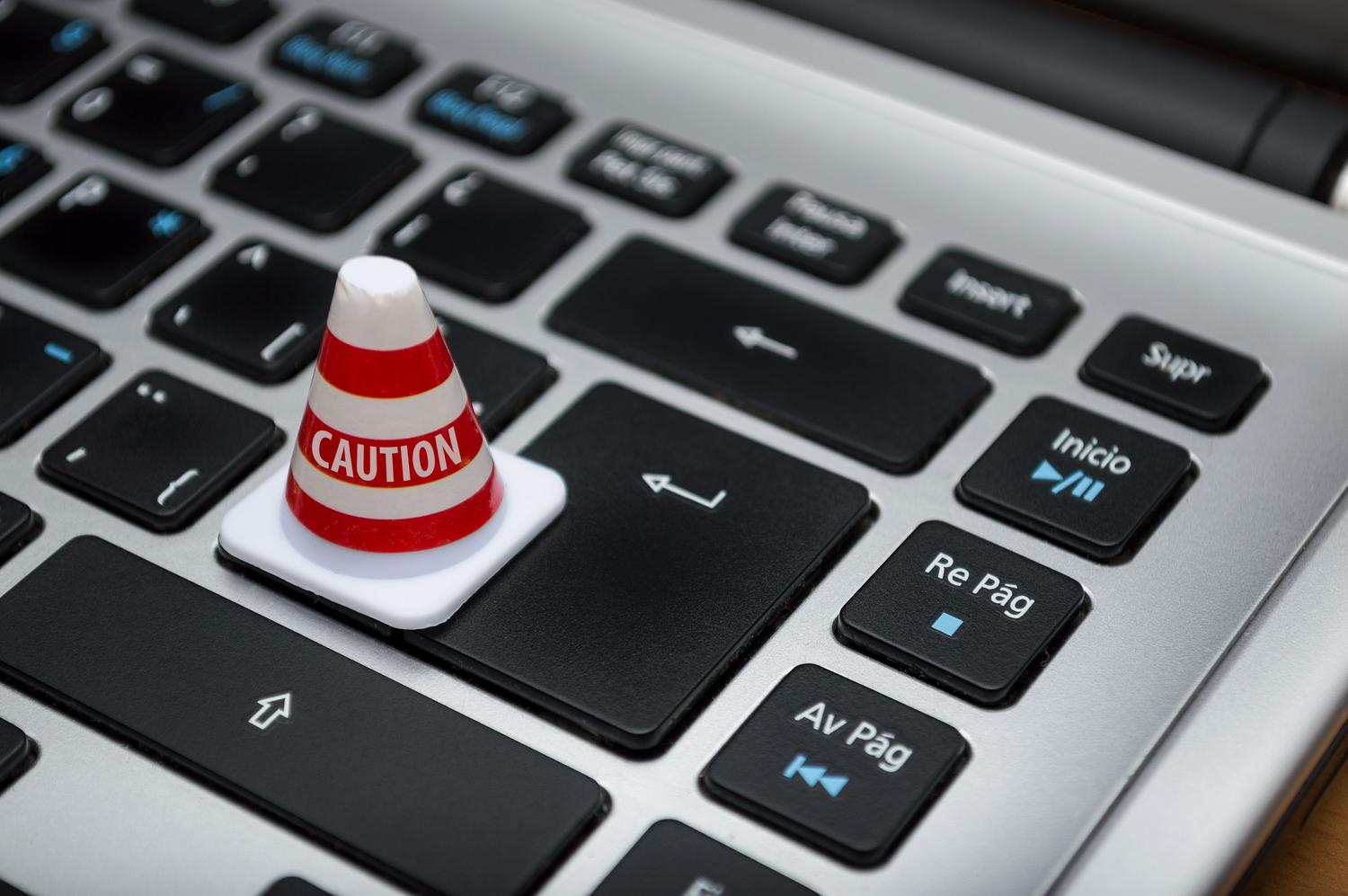 Miniatura de un cono de precaución sobre un teclado de ordenador, simbolizando la necesidad de cautela ante avisos de seguridad.