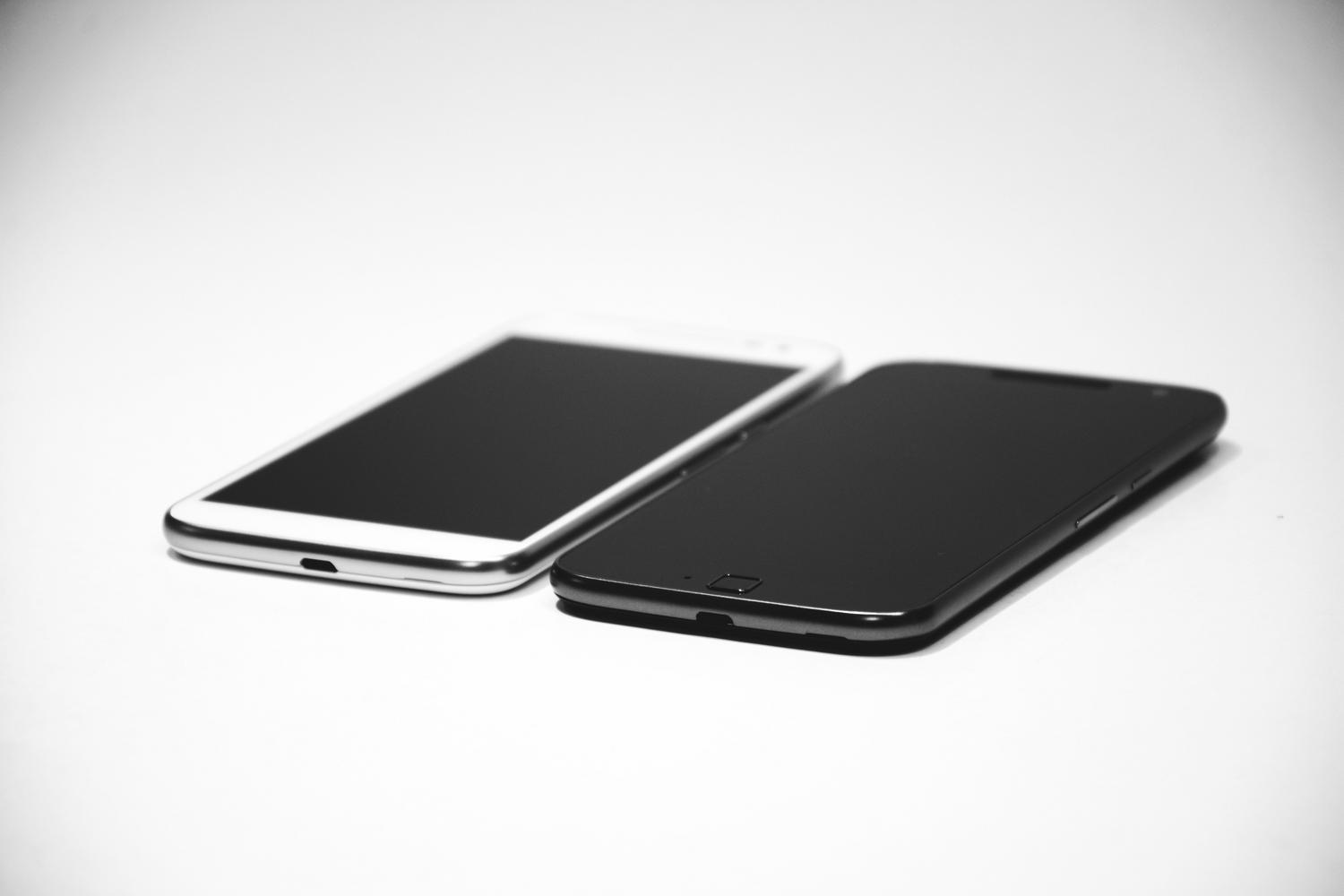 Dos smartphones, uno blanco y otro negro, colocados sobre una superficie blanca, mostrando un diseño moderno y minimalista.