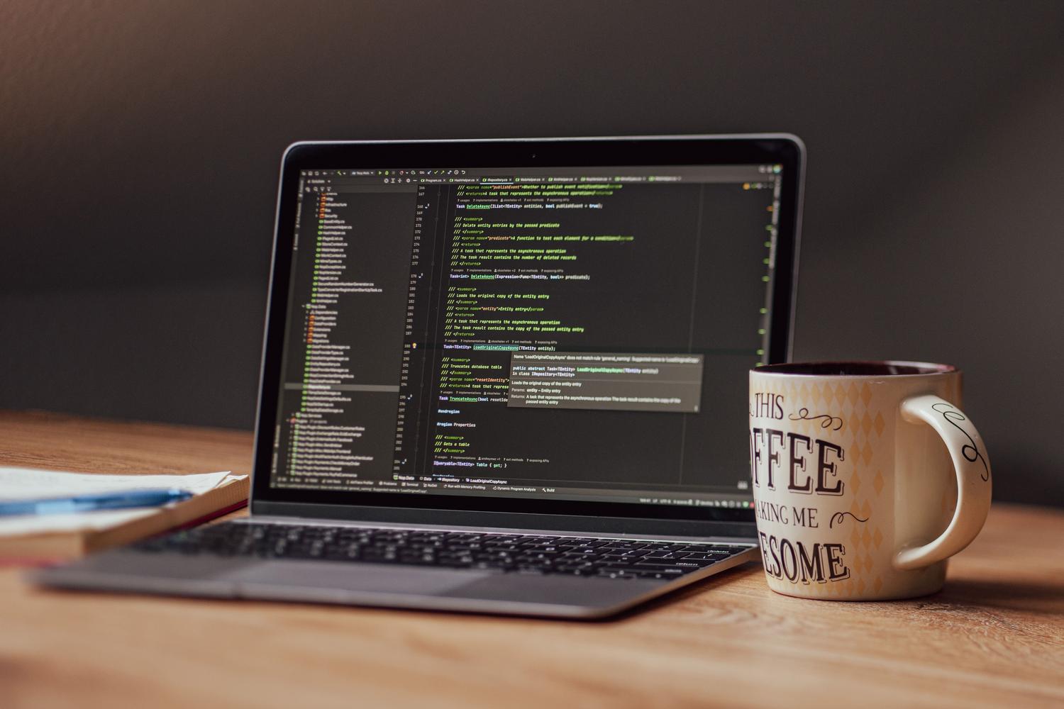 Laptop displaying code editor with coffee mug on desk, representing a professional programming environment
