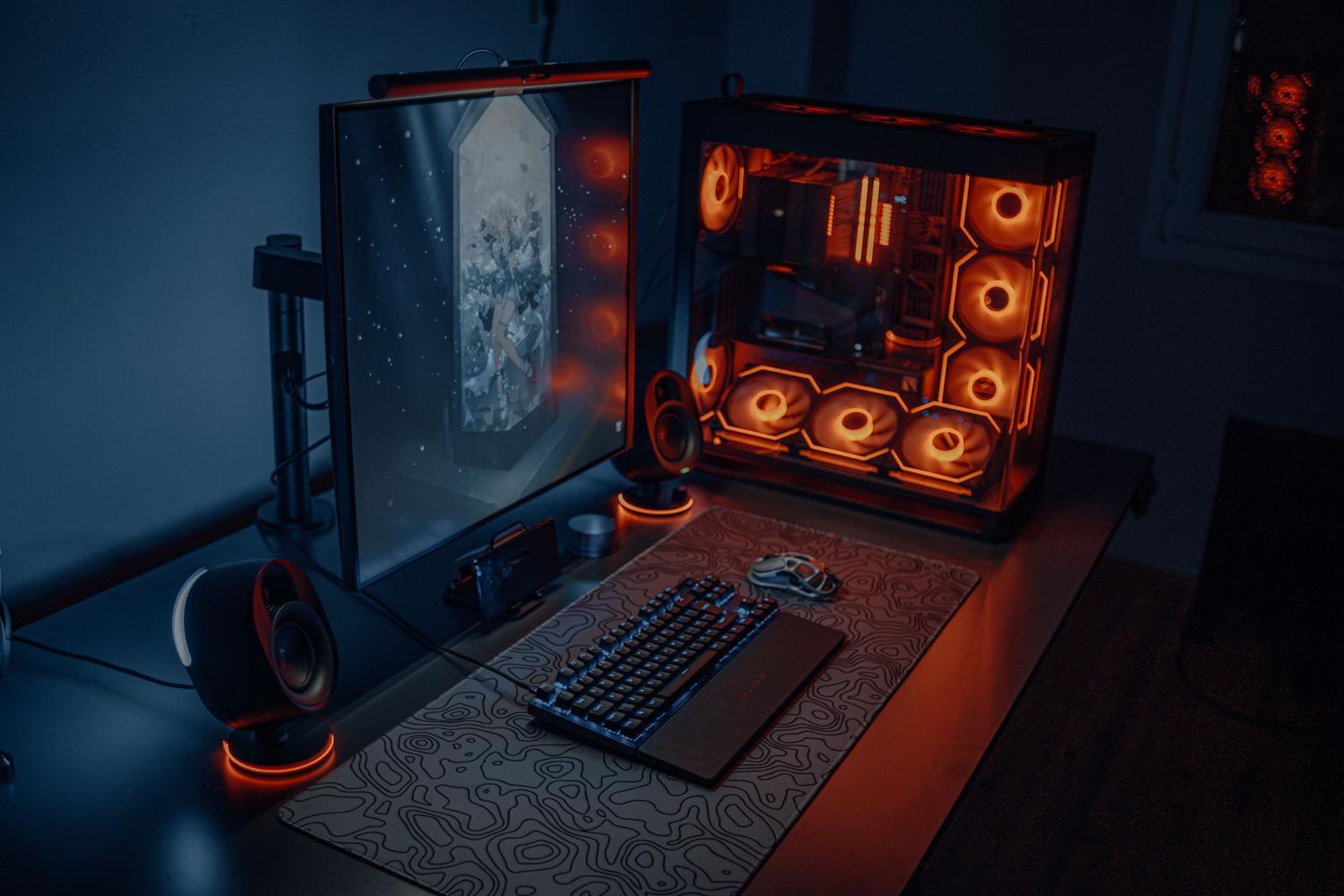 Setup de PC gaming moderno con iluminación RGB, monitor grande y torre con ventiladores luminosos