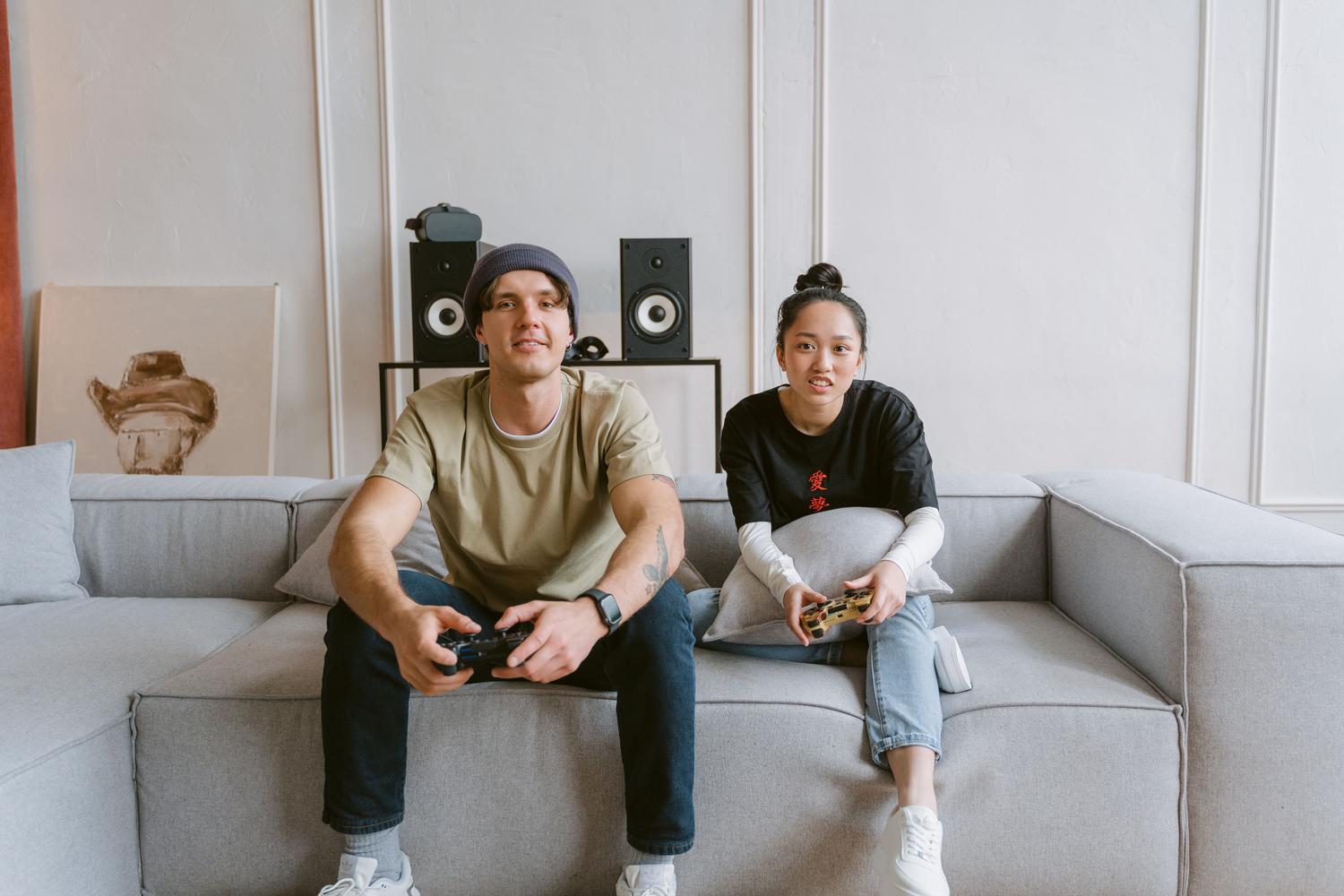 Pareja jugando a videojuegos en un sofá, representando la comodidad de las consolas
