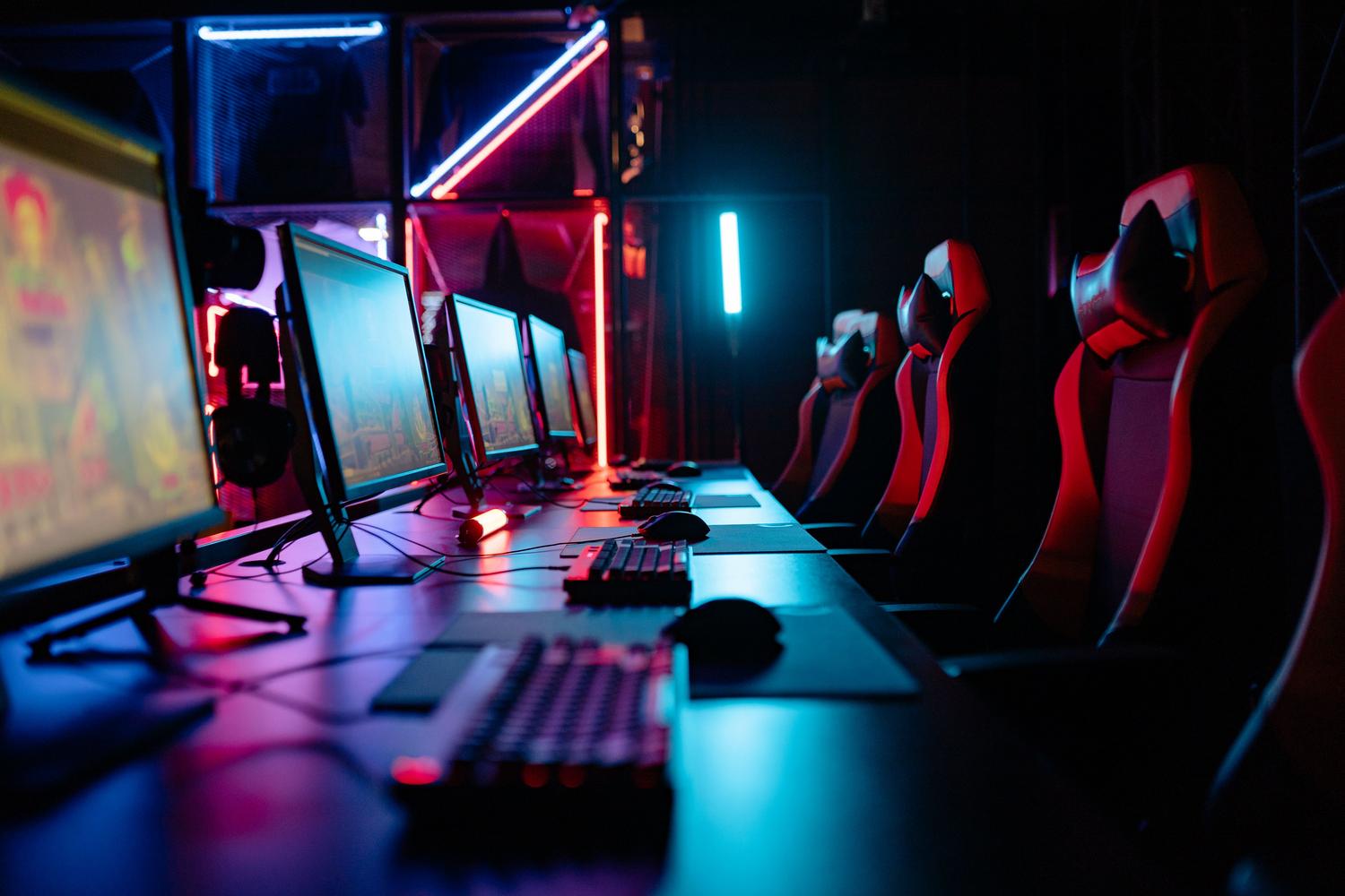 Habitación de gaming inmersiva con luces de neón y múltiples computadoras