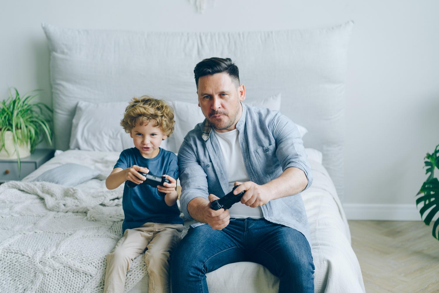 Padre e hijo jugando videojuegos juntos, ilustrando la supervisión del tiempo de juego.