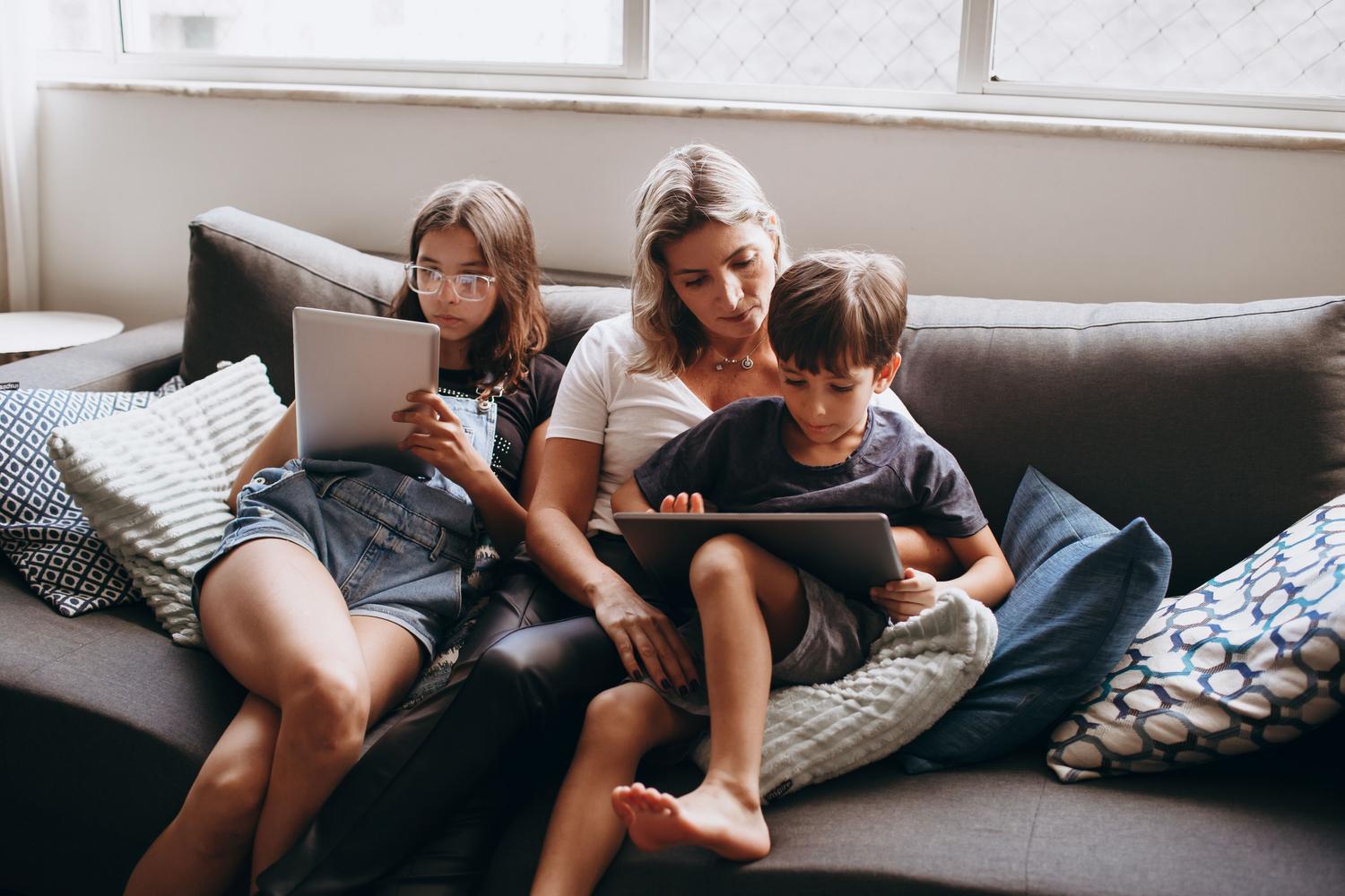 Familia utilizando tablets en el sofá del salón, representando el uso de múltiples dispositivos en casa.