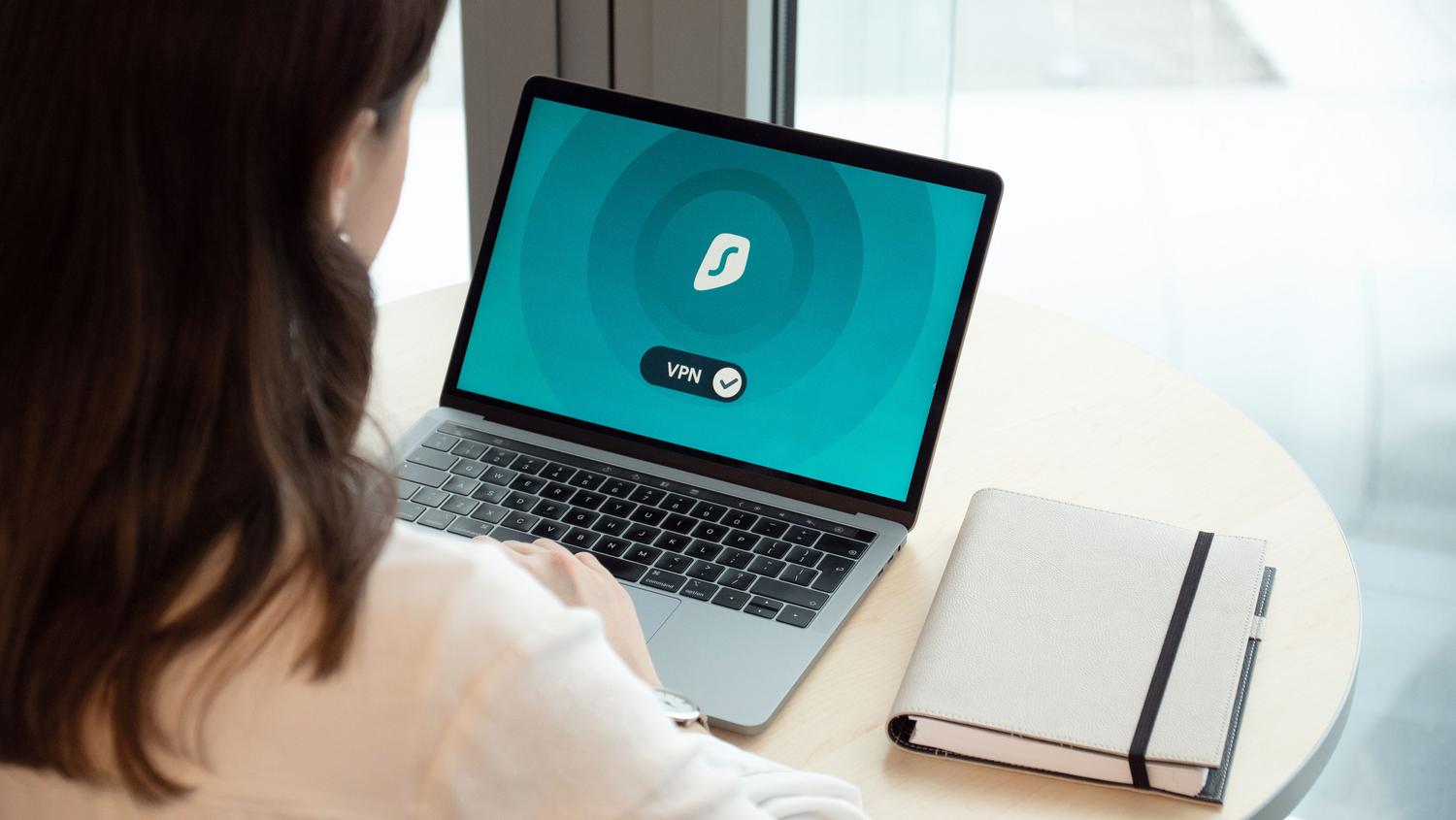 Mujer utilizando un portátil con un icono de VPN en pantalla para navegación segura