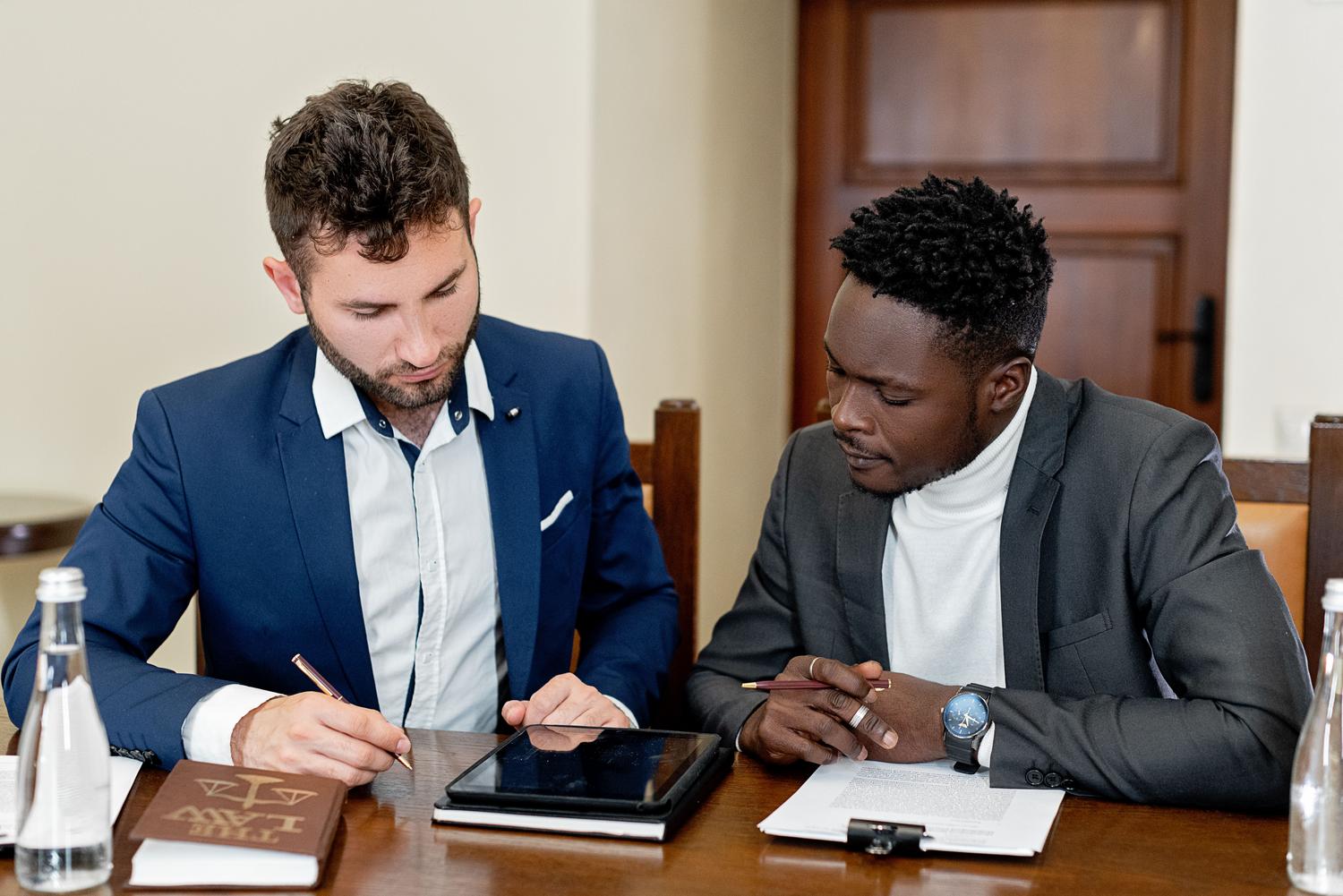 Dos profesionales analizando un contrato digital en una tablet junto a un libro de leyes, representando la validez legal de las firmas.