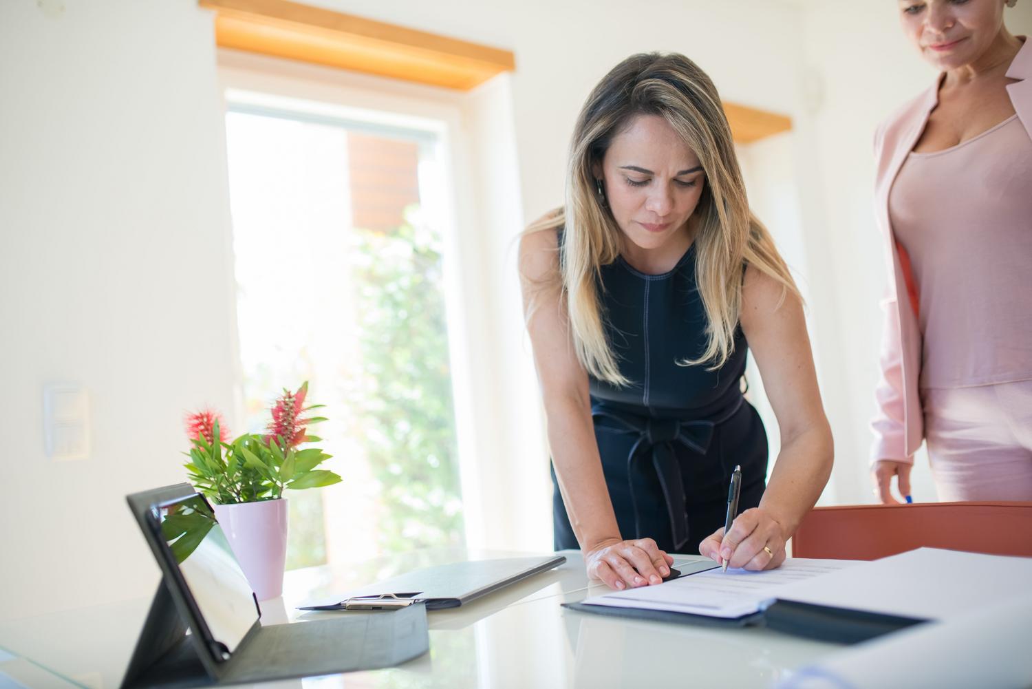 Mujer profesional firmando un acuerdo en una oficina moderna con herramientas digitales a su disposición.