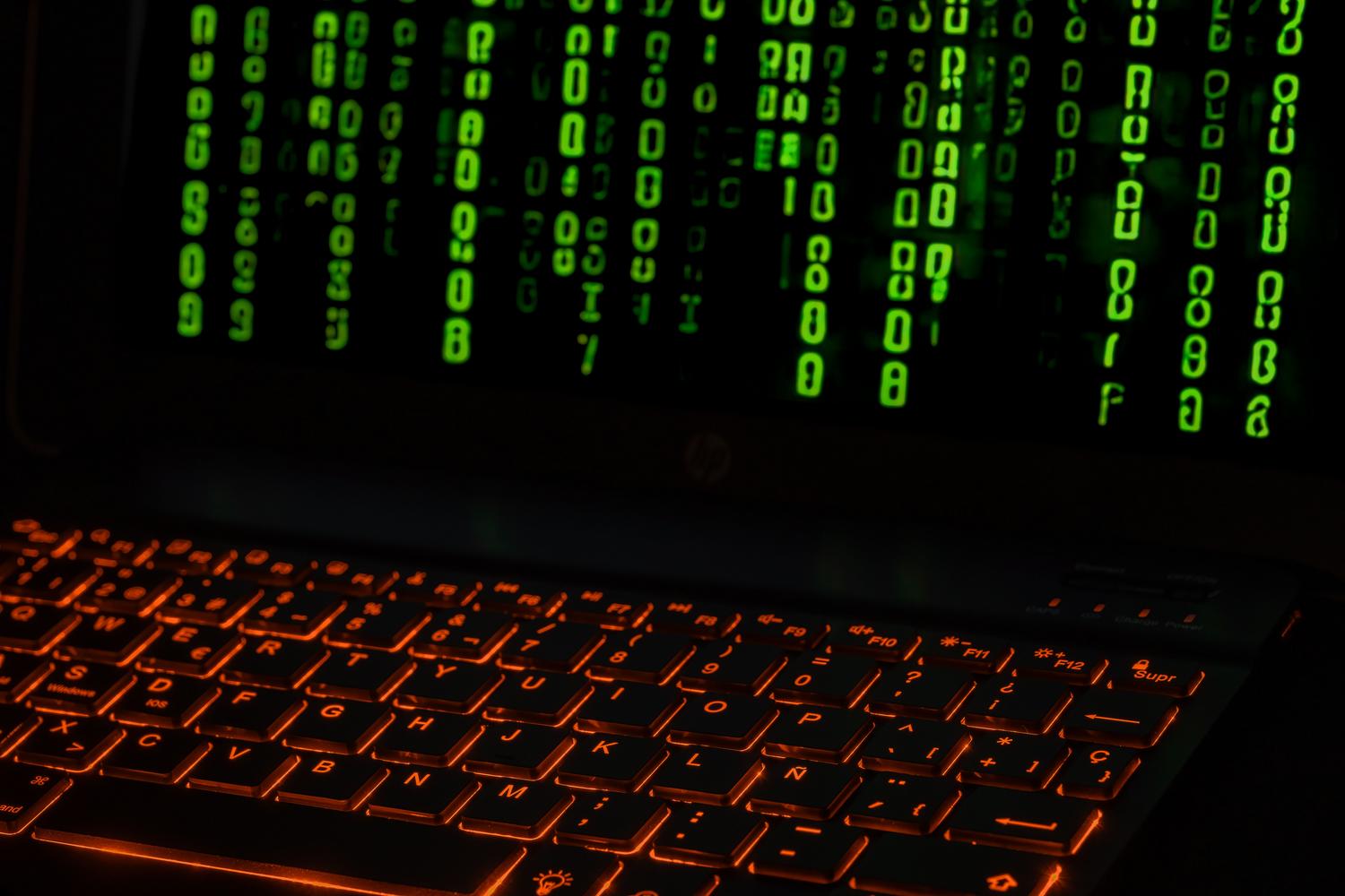Primer plano de un teclado iluminado con código digital verde en pantalla, representando el desarrollo técnico del malware en lenguaje Go.
