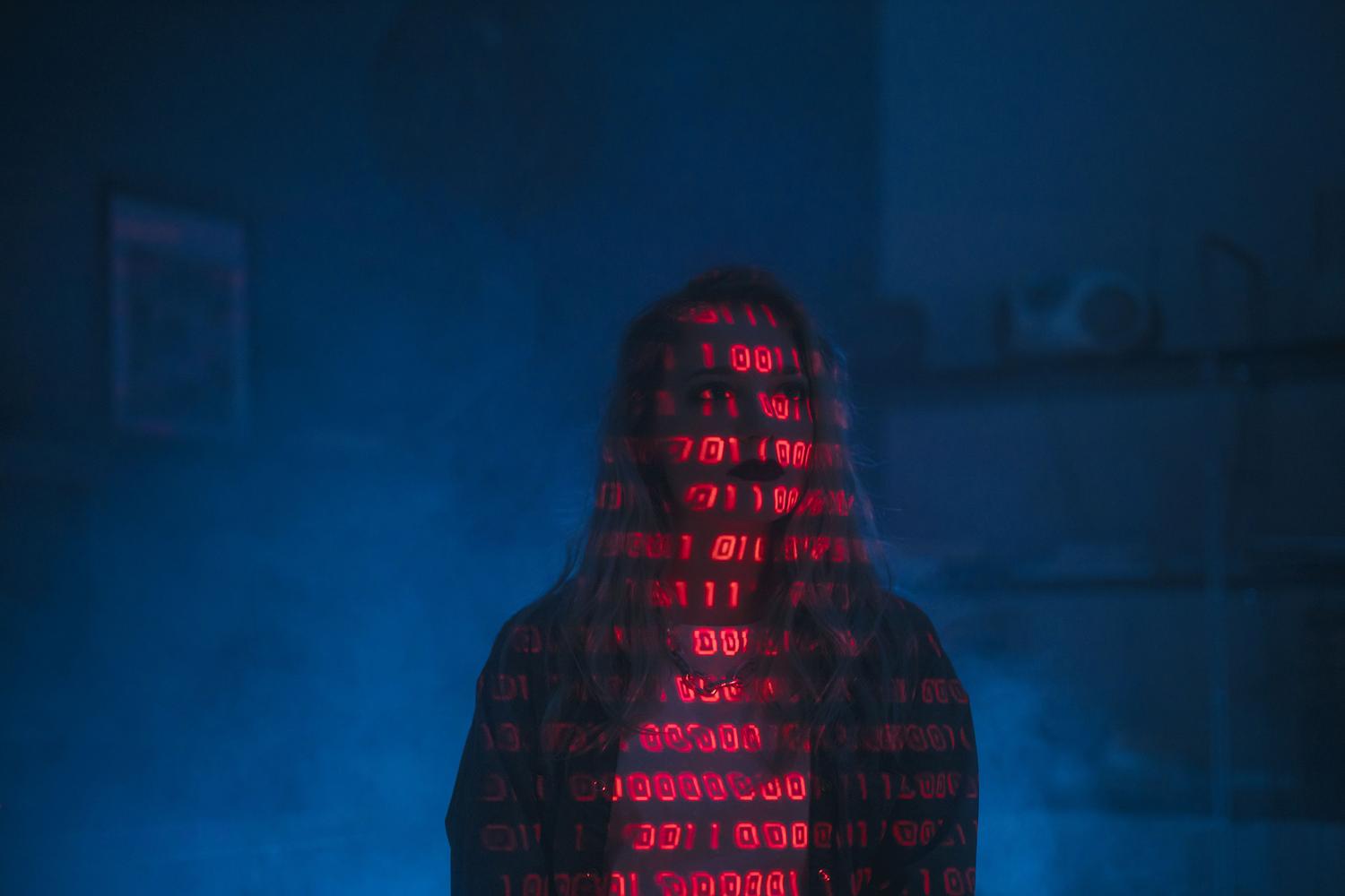 Silueta de una persona con código binario rojo proyectado sobre su rostro, simbolizando una amenaza de malware dirigida por IA.