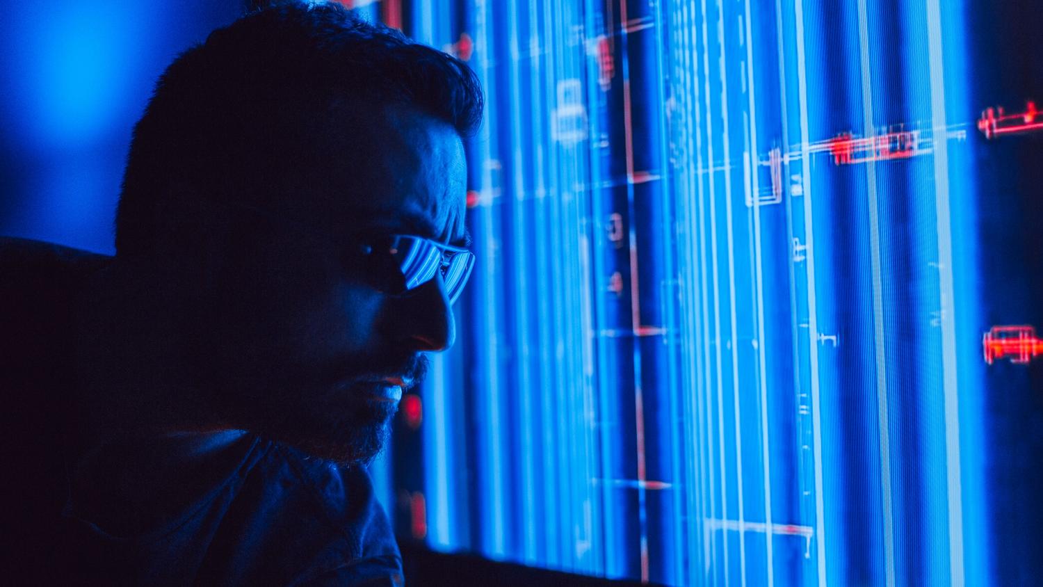 Persona analizando una interfaz holográfica azul con marcadores rojos, simbolizando el proceso de toma de decisiones estratégicas de la IA del malware.
