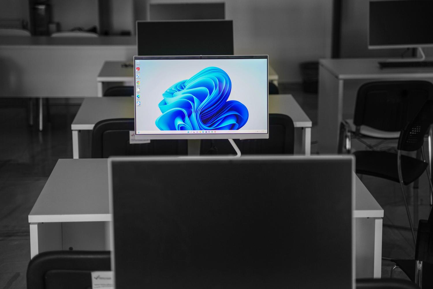 Monitor de computadora en una oficina moderna y minimalista mostrando el escritorio de Windows 11, ideal para representar un entorno de trabajo estándar.